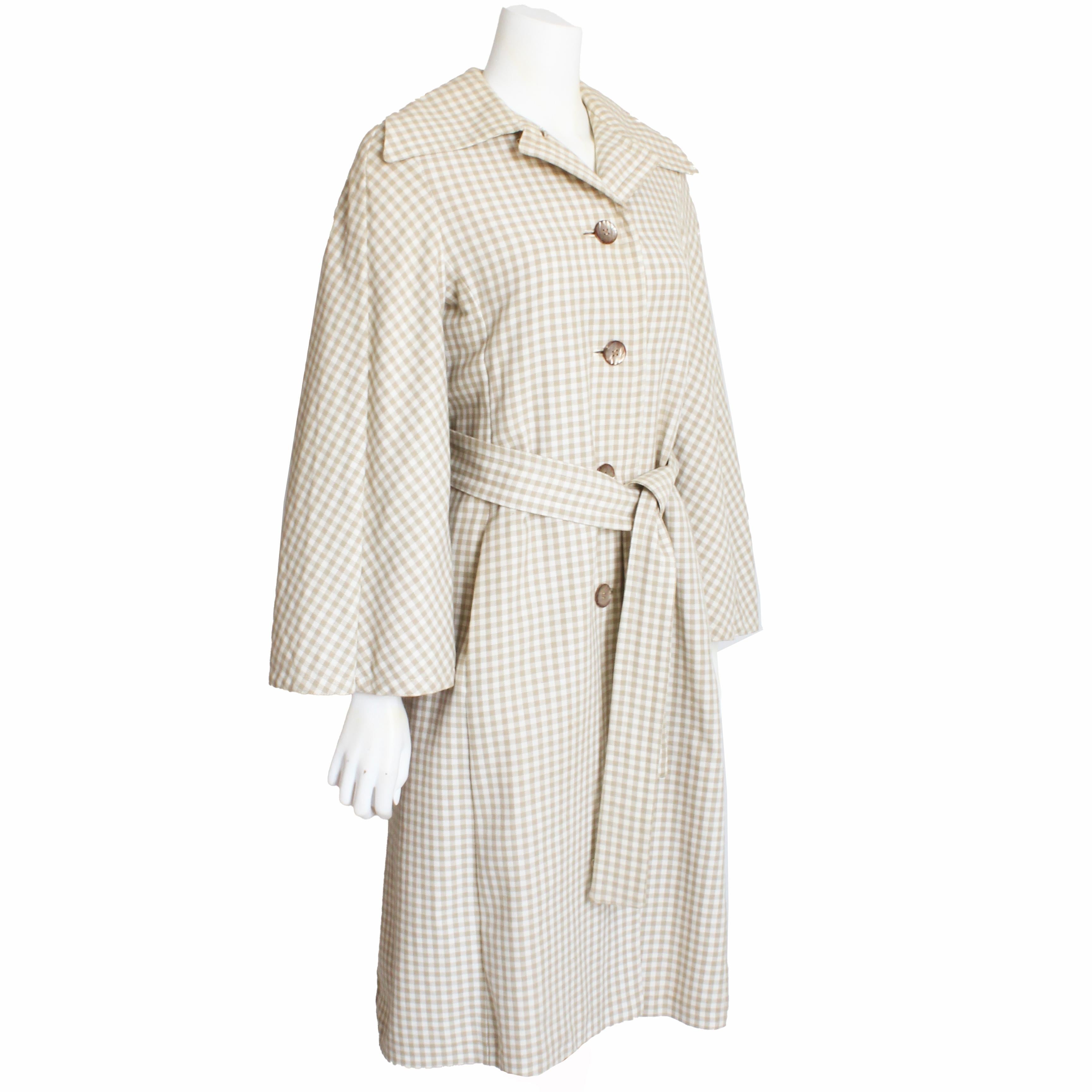 Authentischer, gebrauchter Mantel oder Jacke im Trenchcoat-Stil von Donald Brooks mit angesetztem Umhang, circa in den 70er Jahren. Er ist aus leichtem hellbraun-weiß-kariertem Webstoff gefertigt, wird mit Knöpfen geschlossen und mit einem