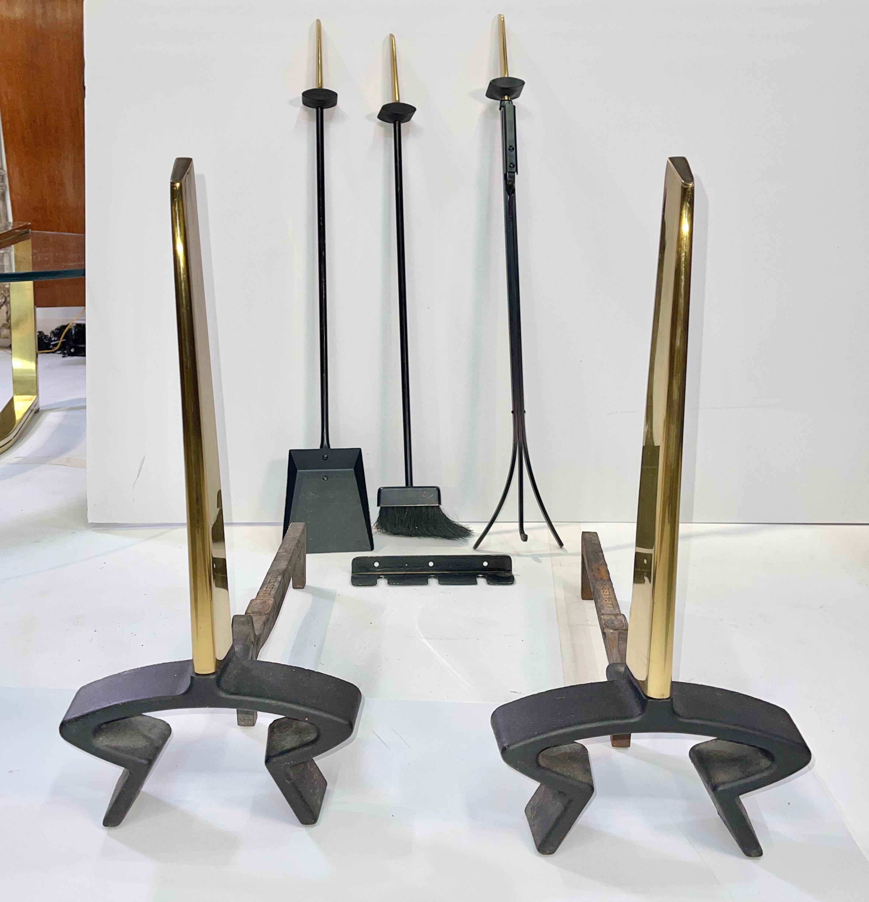 An original five piece set of modernist Art Deco andirons and matching fireside tools designed by Donald Deskey and produced by Bennett-Ireland Company of Norwich, NY. Sculptural hefty brass handles on the broom, shovel and claw poker. The three