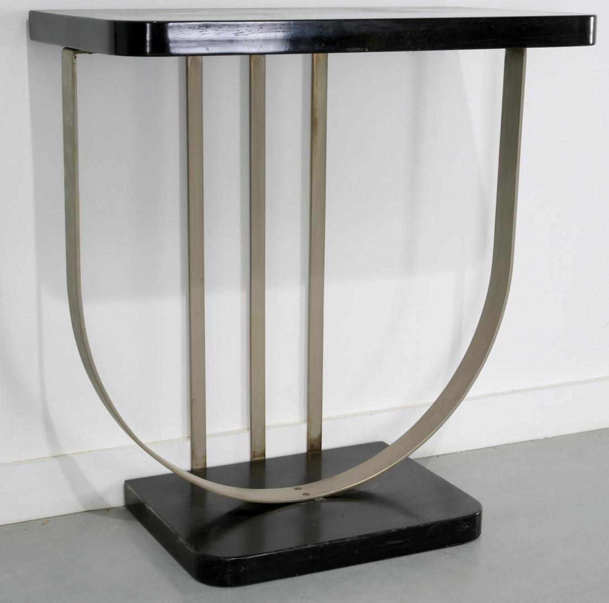 Donald Deskey attributed console and mirror, 1930s, USA, black lacquered wood, nickeled brass, in the Art Moderne style, the rectangular console top raised on curved flat bar metal supports, with associated rectangular mirror with black lacquered