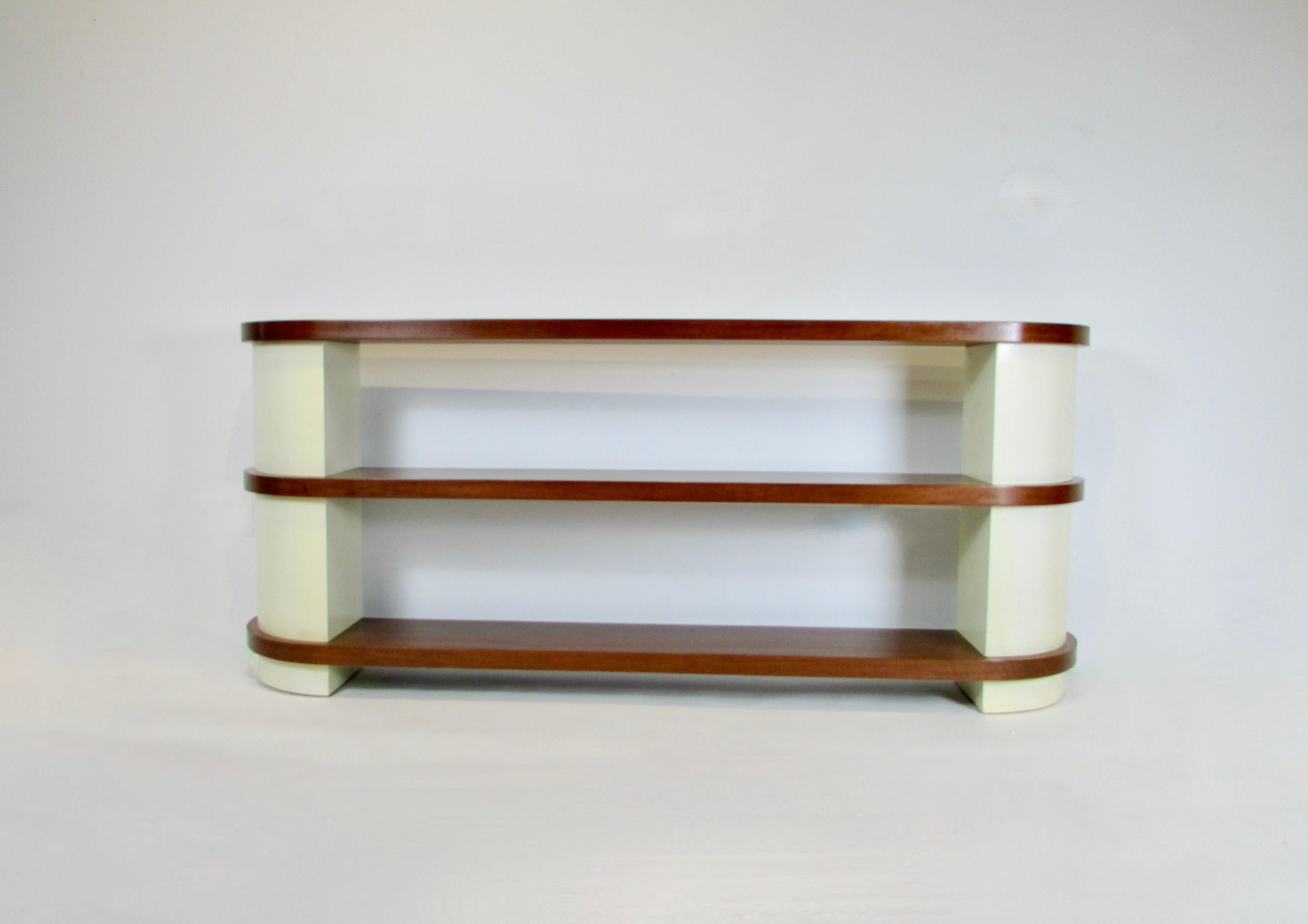 If not Donald Deskey certainly in his style  . Well made Classic streamlined moderne shelves . Three walnut shelves accented and separated by cream lacquered quarter round  fillers . Believed to be older refinish in fine condition . There does
