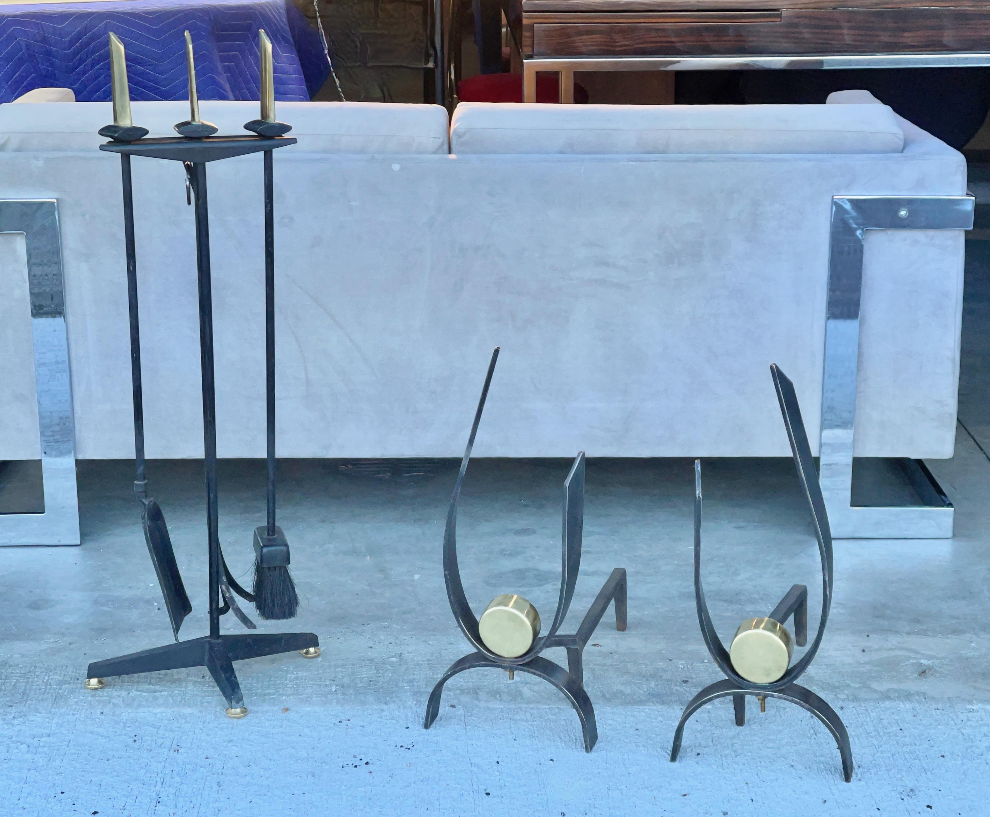 An original 4 piece set of modernist Art Deco fireside tools designed by Donald Deskey. Sculptural hefty brass handles on the broom, shovel and claw poker. The three tools rest in a standing bracket on tripod base with brass feet. Deskey's design