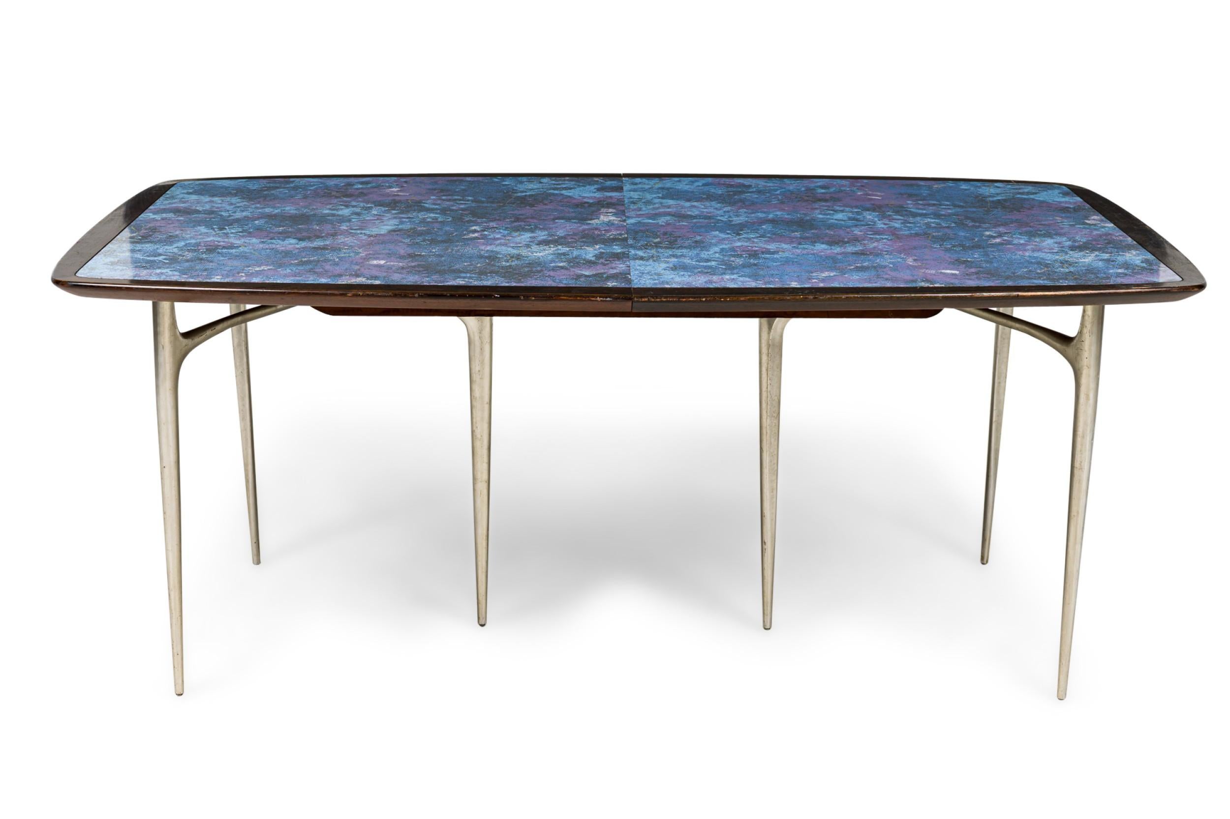 Mid-Century American Modern extension dining table with a blue marbled enamel top with a black edge resting on two burnished aluminum tripod form bases in a sculptural and minimalist form, tapering toward the center and leg bottoms. (2 leaves @ 18