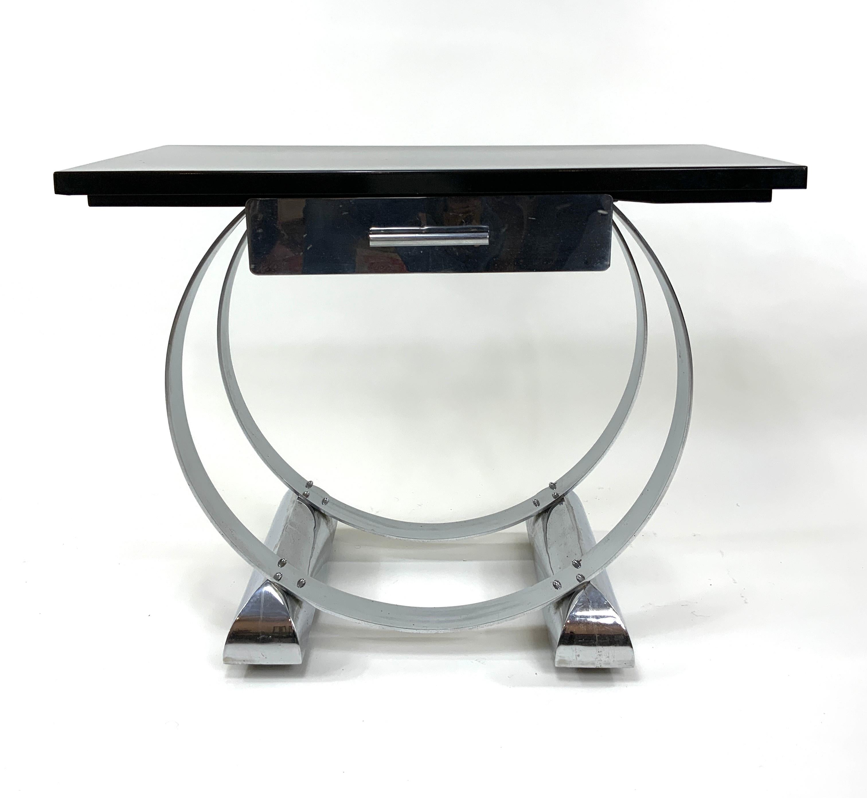 A magnificent Art Deco console table in the style of Donald Deskey featuring two concentric circular chromed metal flat iron bars mounted on two unusual and splendidly-shaped chromed metal bases. The latter conceal wheeled castors which permit easy
