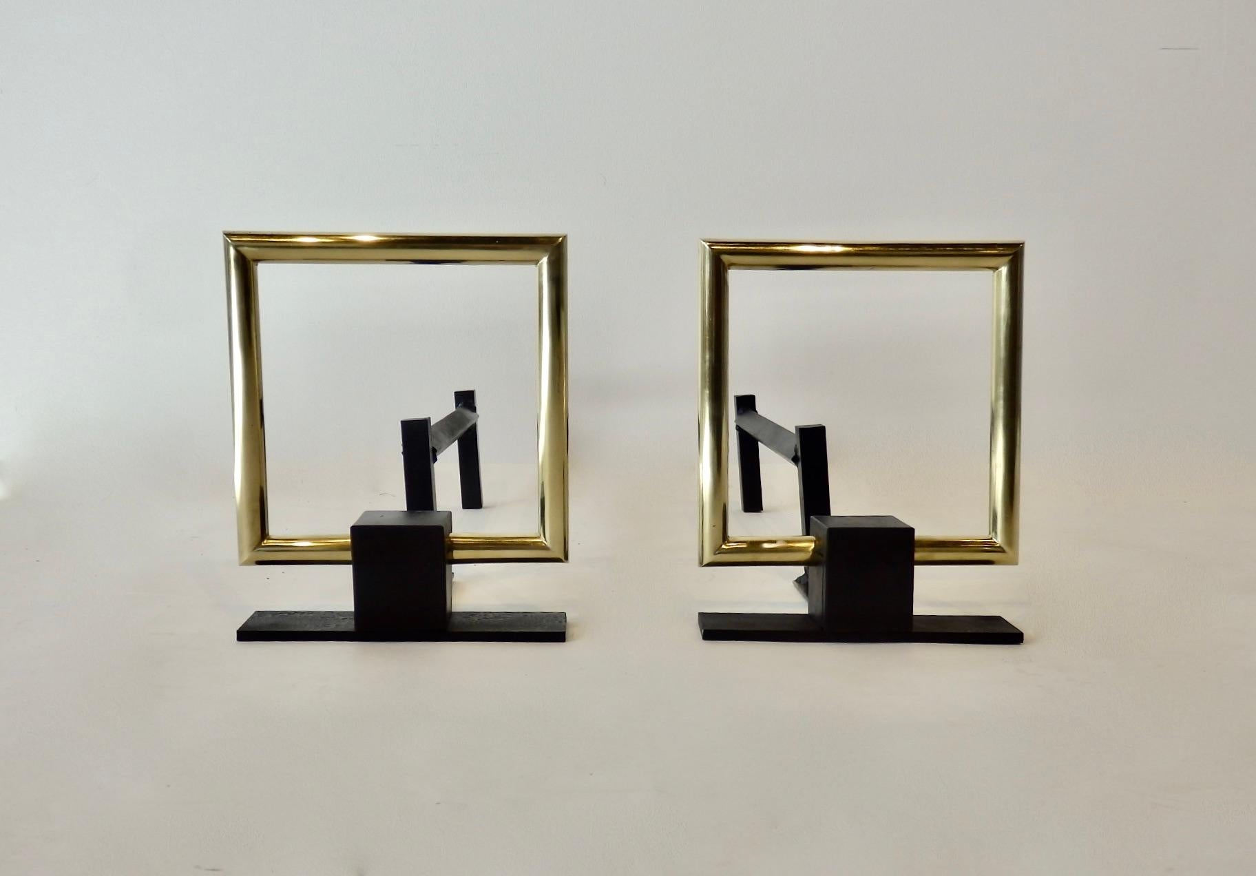 Art Deco styled geometric fireplace andirons. Polished brass square set in cast iron stand. Style of Donald Deskey known for so many Machine Age fireplace items. Brass square is 3/4 polished round stock measures 8 x 8. Shipped disassembled.