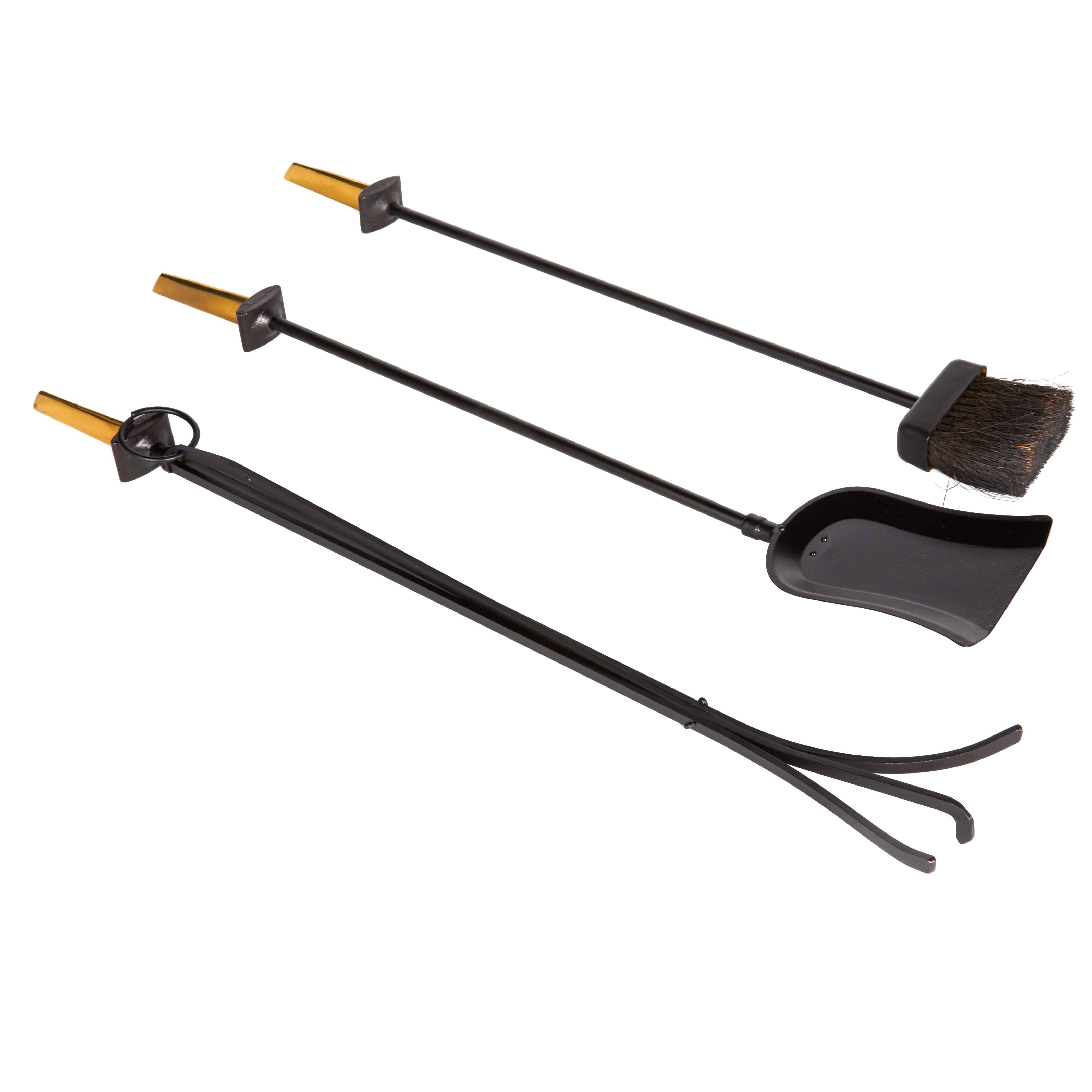 Mid-Century Modern fireplace tool set by iconic 20th century designer Donald Deskey, for the Bennett Company. The set features a wall-mounted backplate which houses the shovel, brush and poker. The tools are all made of wrought iron with a black