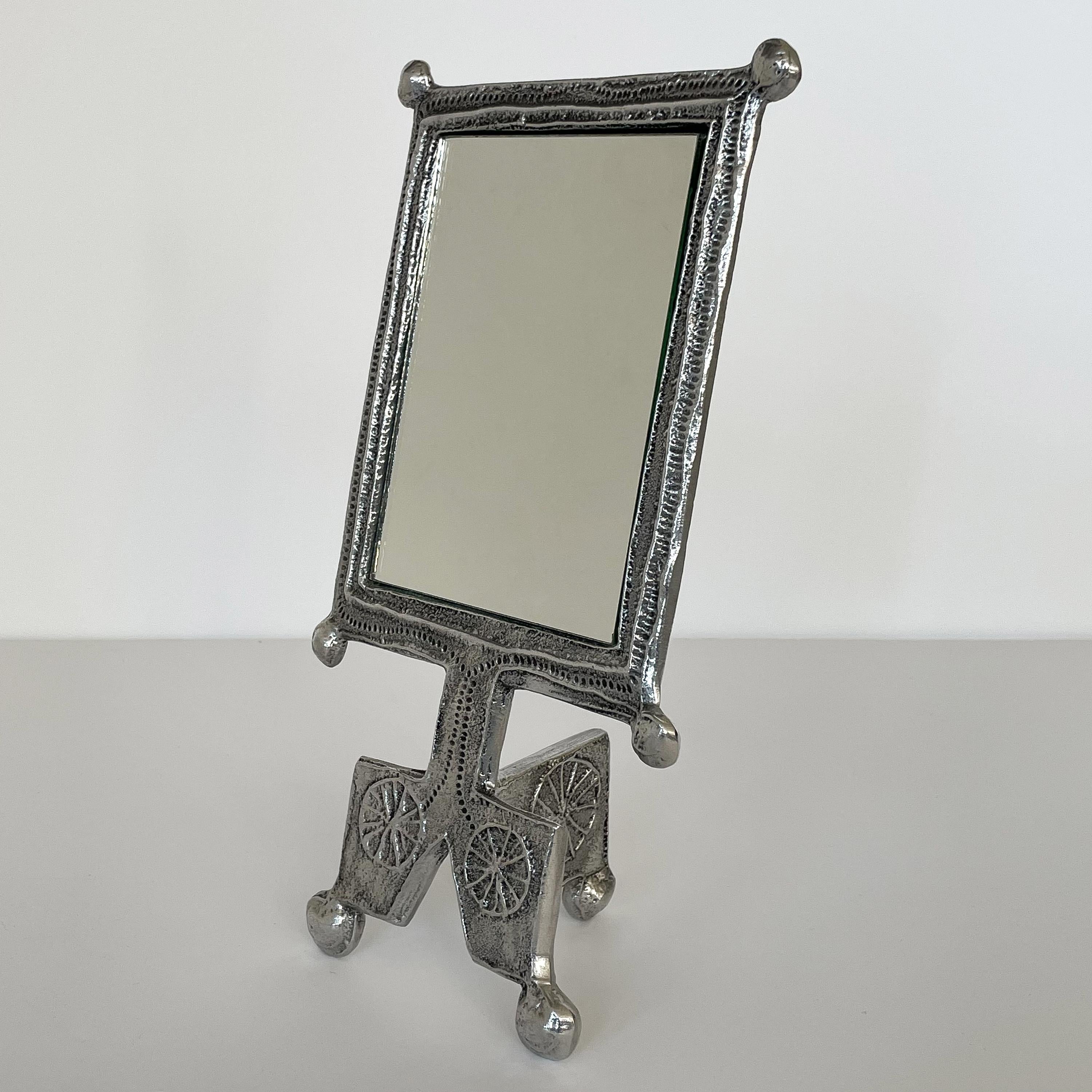 Donald Drumm aluminum standing vanity mirror with face. Brutalist cast aluminum frame and tripod stand. Rectangular mirror measures 5