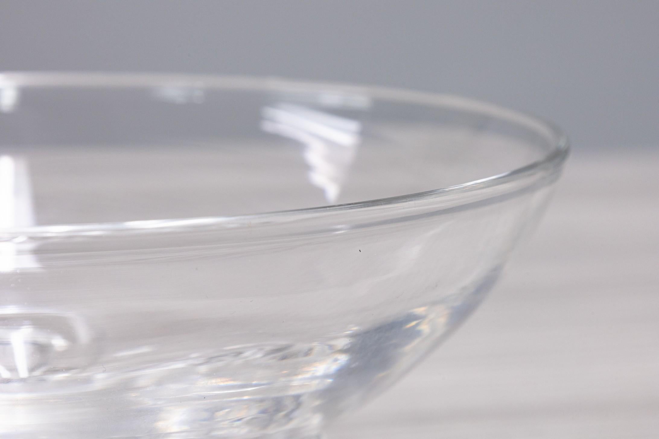 Un étonnant bol classique en verre de Steuben de l'artiste Donald Pollard. Cette petite coupe en cristal présente un élégant bord fin, qui descend jusqu'à trois pieds en boucle entourant la base. Cette pièce est signée sur la face inférieure. Il