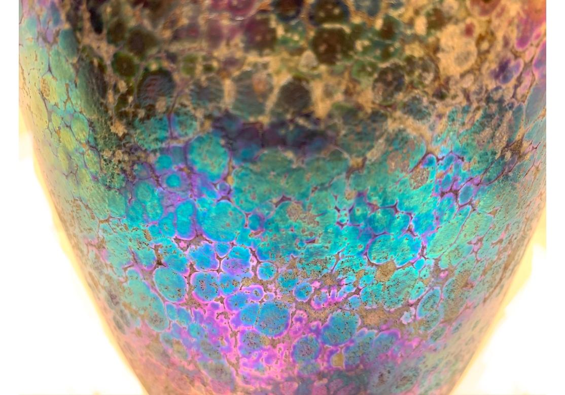 Vaso in vetro artistico di grandi dimensioni con sfumature di viola, oro, blu e verde e una leggera texture. Firmato e datato sul verso. Donald W. Friel 1981.

Dimensioni: 5 1/2