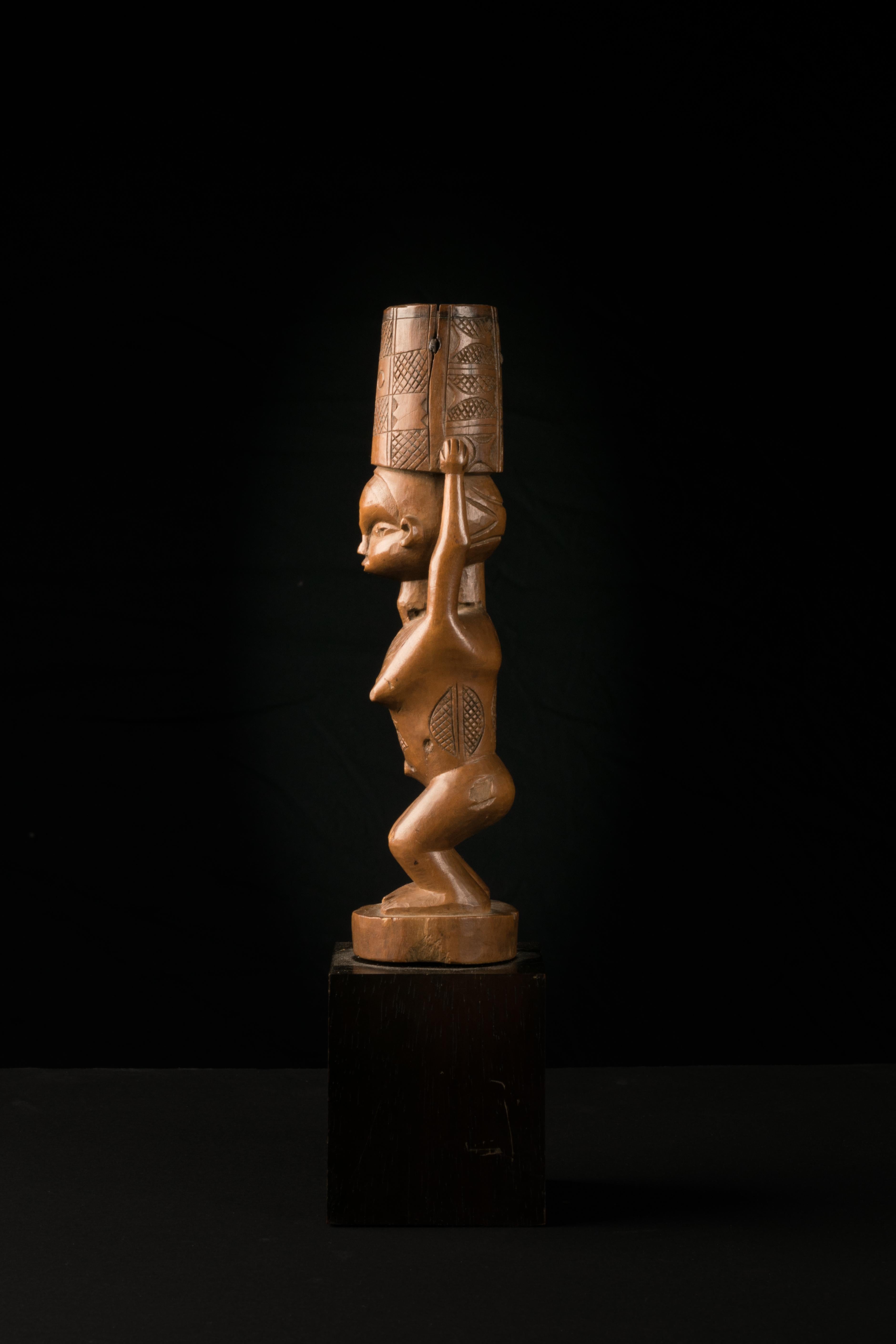 Flywhisk handle sculptured in the form of a woman with slightly bended Knees and Scarification’s on different parts of her body. She is holding a vessel that kept a ponytail. This Flywhisk was part of a Chief's Regalia.
Provenance: ancient