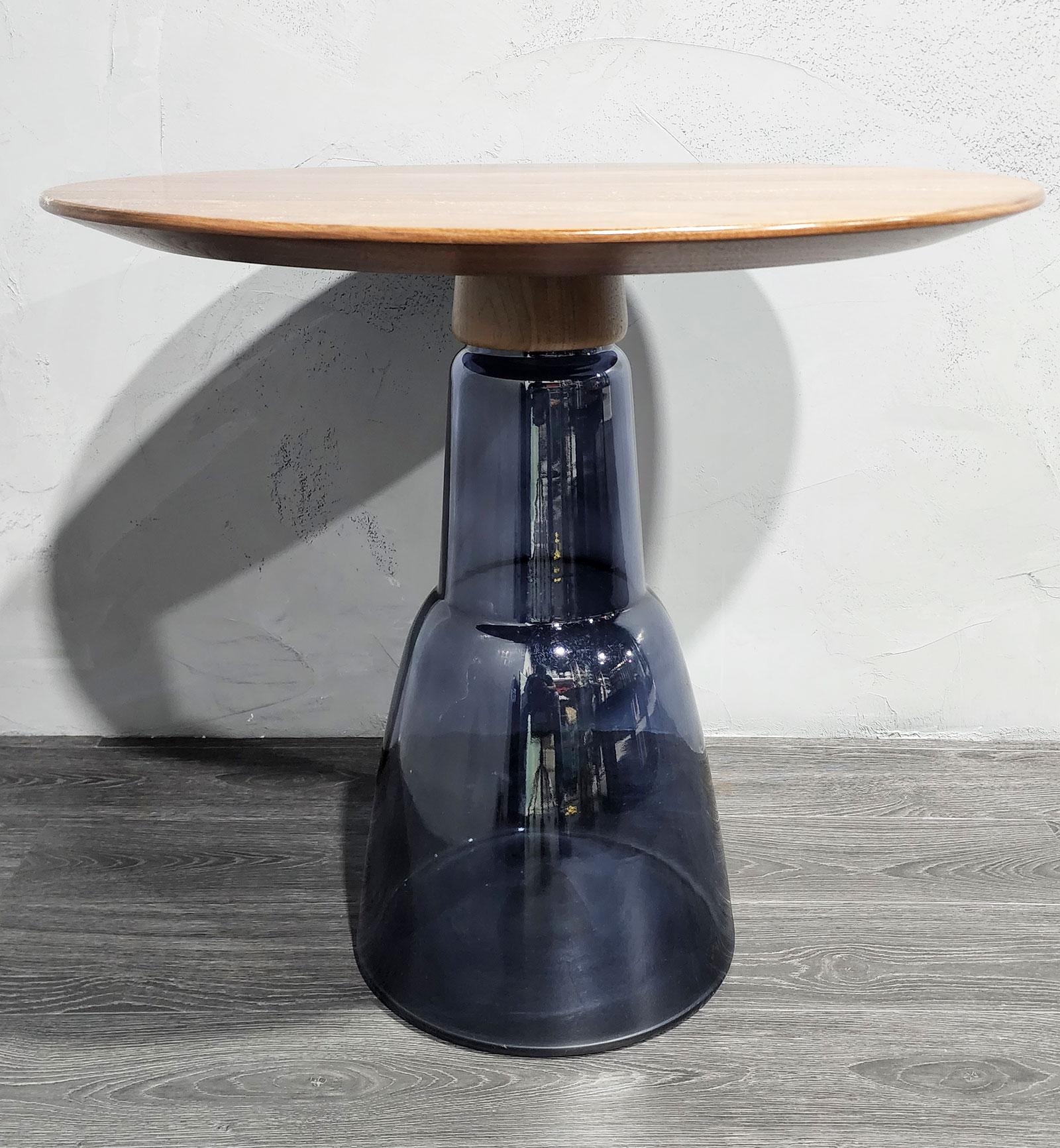 Round side table featuring a tinted Venetian blown glass base and an American walnut, compound curve veneered top. Inspired by the legendary Alchemist's alembics, its one-of-a-kind combination of materials makes this piece the gracefully light,
