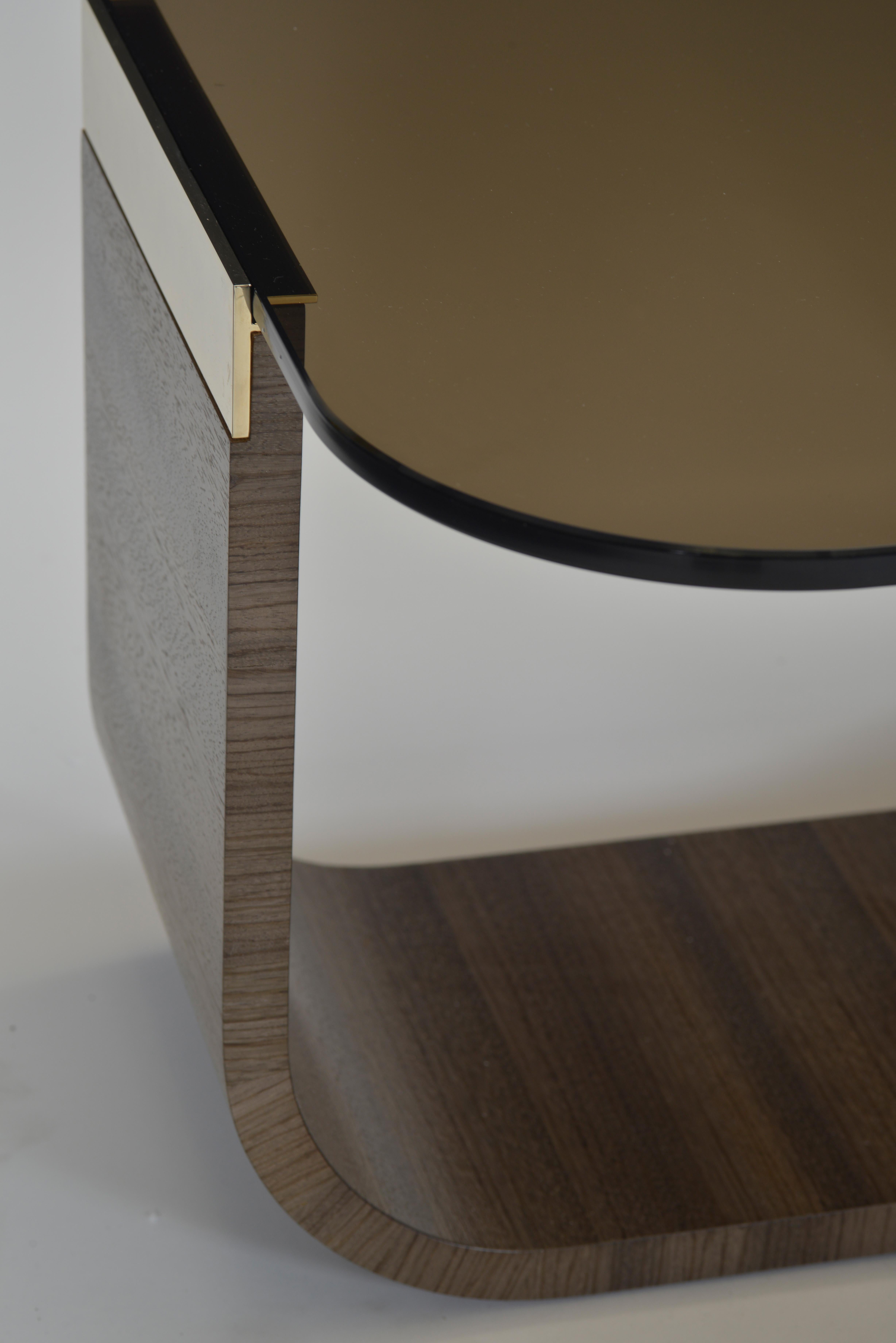 Cocktail table with gold-plated accents in choice of grigio leather or gray Zebrano veneer. The leather base comes standard with stitching accenting the perimeter. Options for the top include bronze glass or white limestone. Overall dimensions of