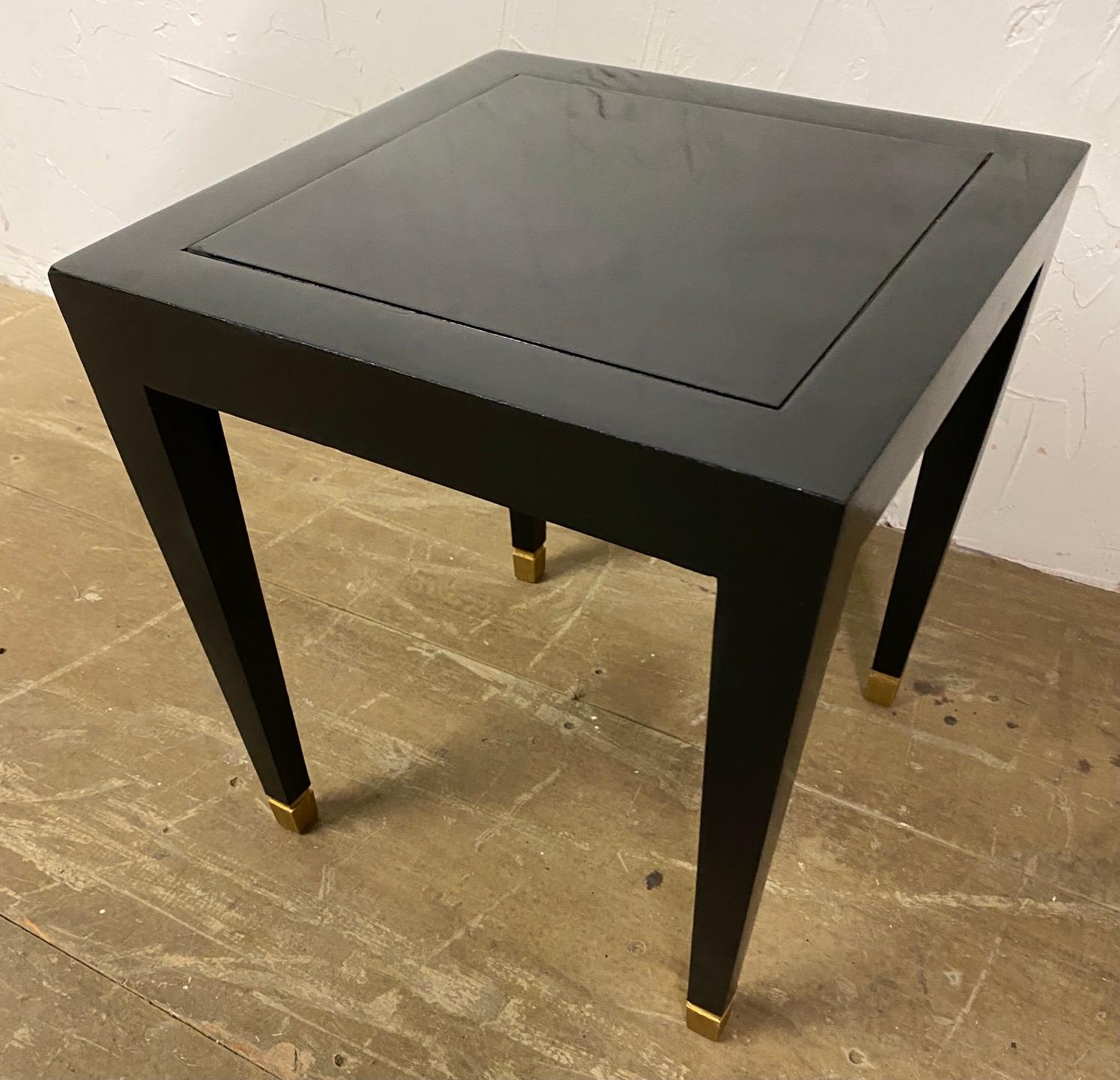 Stylish small black lacquered Donghia Mardrid side table with tapered legs and square brass caps. Great small table to set beside a chair or sofa to set a drink down on. The table can be moved easily to suit many needs. A second shorter matching 16