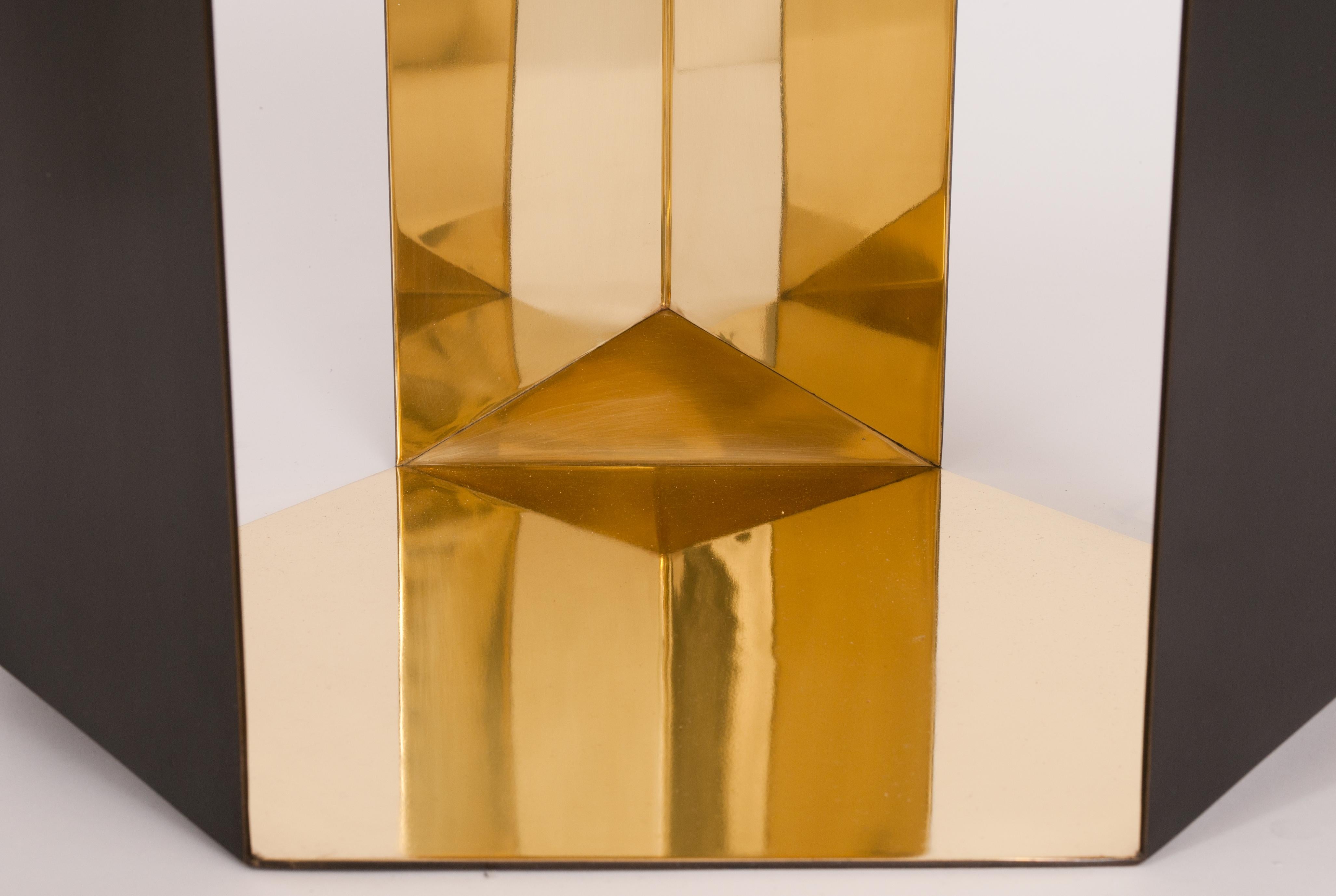 Inspired by folding paper and realized in sheet metal, this table's shape has a bold geometric design that is distinct in any application. The origami cocktail table has an exterior antiqued hand-rubbed patina finish and mirrored interior finish.