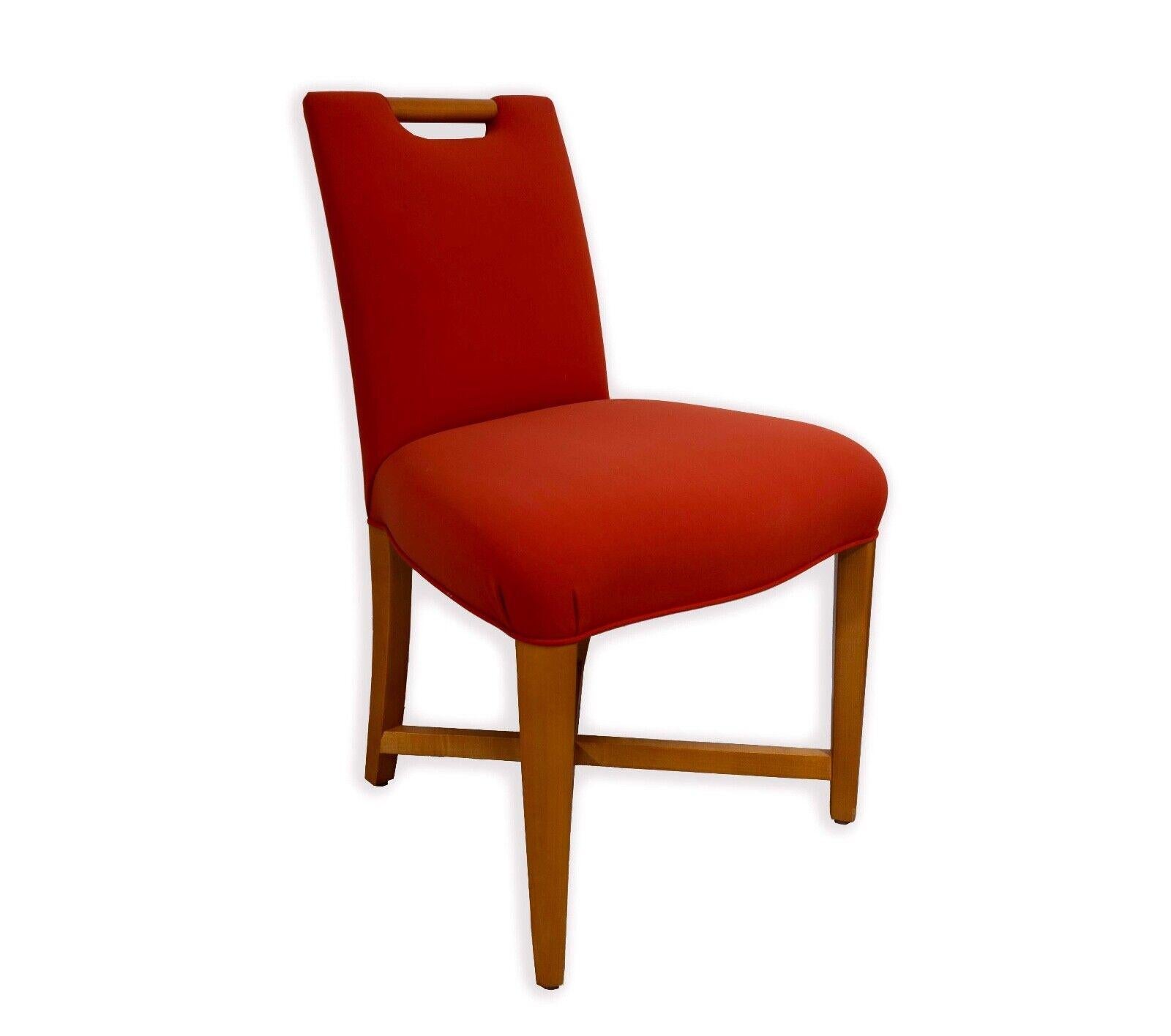 This set of four Donghia mid-century modern side chairs, a testament to timeless design and quality craftsmanship. Each chair features a vibrant orange upholstered seat and backrest, providing a bold pop of color and a touch of retro flair. The warm