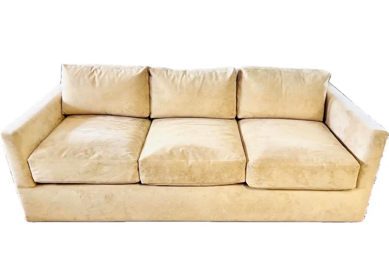 Elegant Donghia three seater sofa with clean classic lines and upholstered in a neutral tan suede fabric.  It sits beautifully and does not need to be reupholstered.  Note there is one very small nick in fabric on back so it is invisible and we have