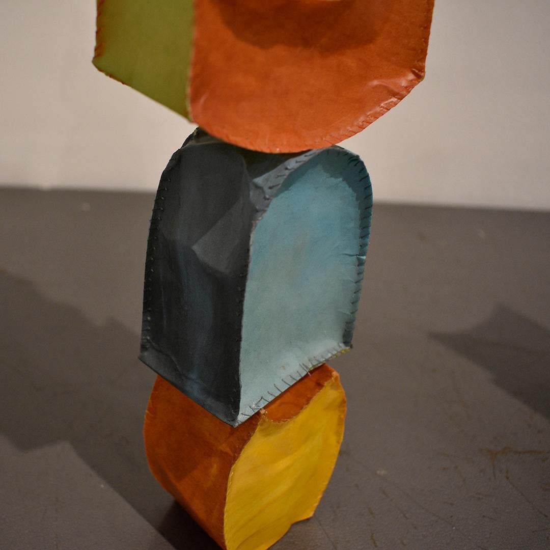 Sculpture abstraite tridimensionnelle sur pied dans des tons colorés de bleu ciel, orange sanguin, vert, jaune et rose
