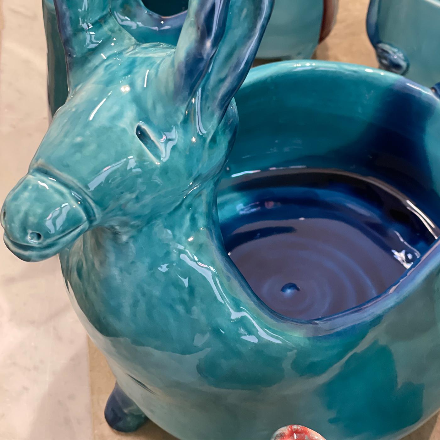 A Unique, smiling donkey statuette can be used as a small plant holder, bread basket, or flower vase. Handmade of white ceramic with embossed wings, and decorated with crystal clear and colored enamels, this piece will add a cheerful touch to any