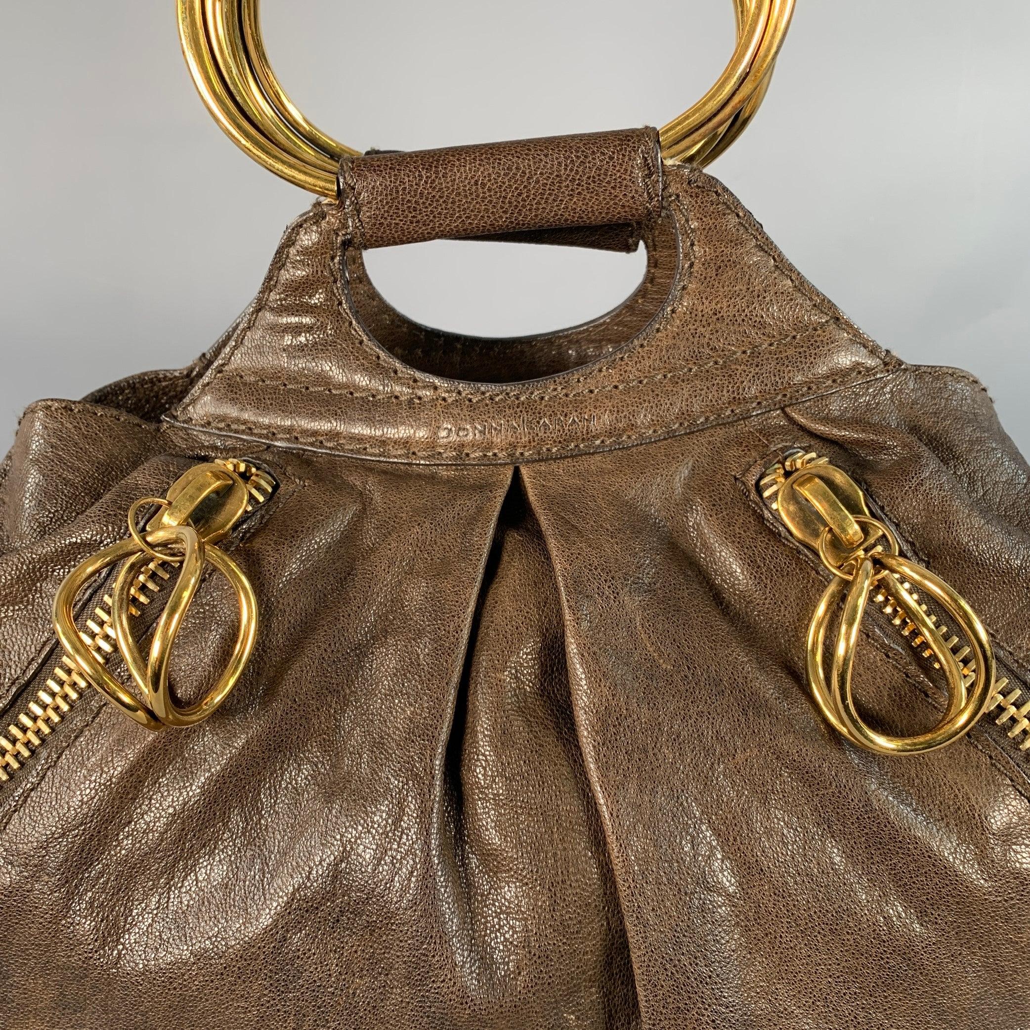 Borsa Donna Karan
in pelle di capra marrone con manici in metallo dorato, quattro tasche con zip in metallo dorato e parte superiore aperta. 

Misure: 
  Lunghezza: 17 pollici Larghezza: 8 pollici Altezza: 11,5 pollici Altezza: 3 pollici 
  
  
