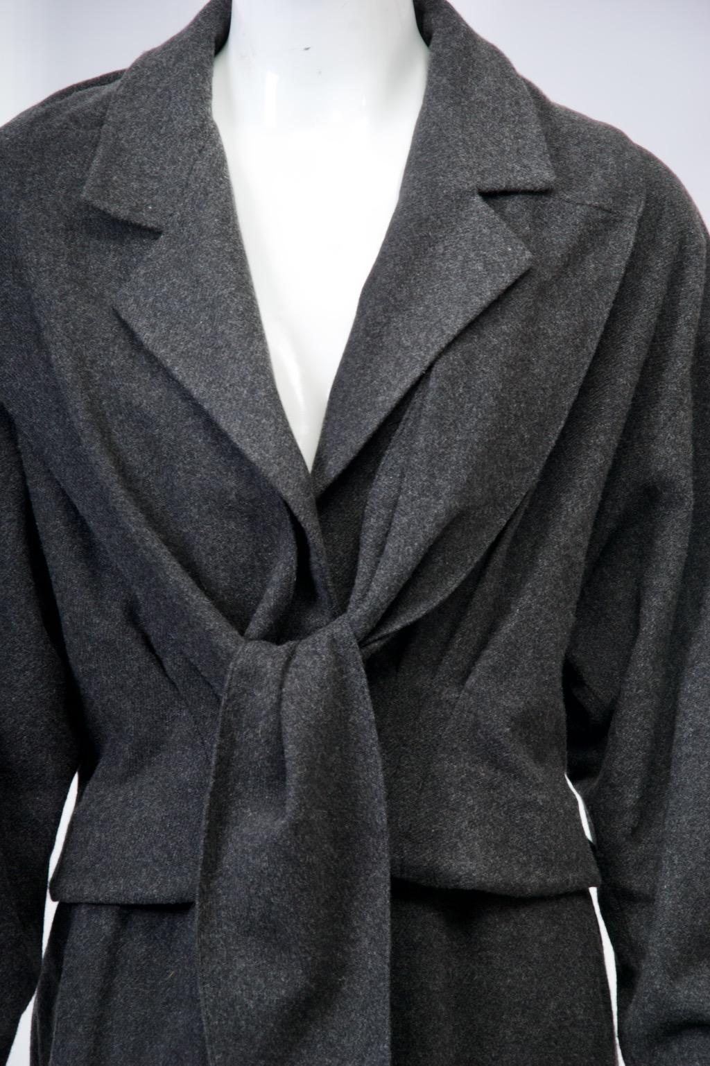 Chic luxury from master designer Donna Karan c.1990s, this suit is crafted of charcoal gray cashmere, a subtle extravagance for a tailored ensemble. The suit is comprised of a straight skirt that hits below the knee and a fitted, short jacket that