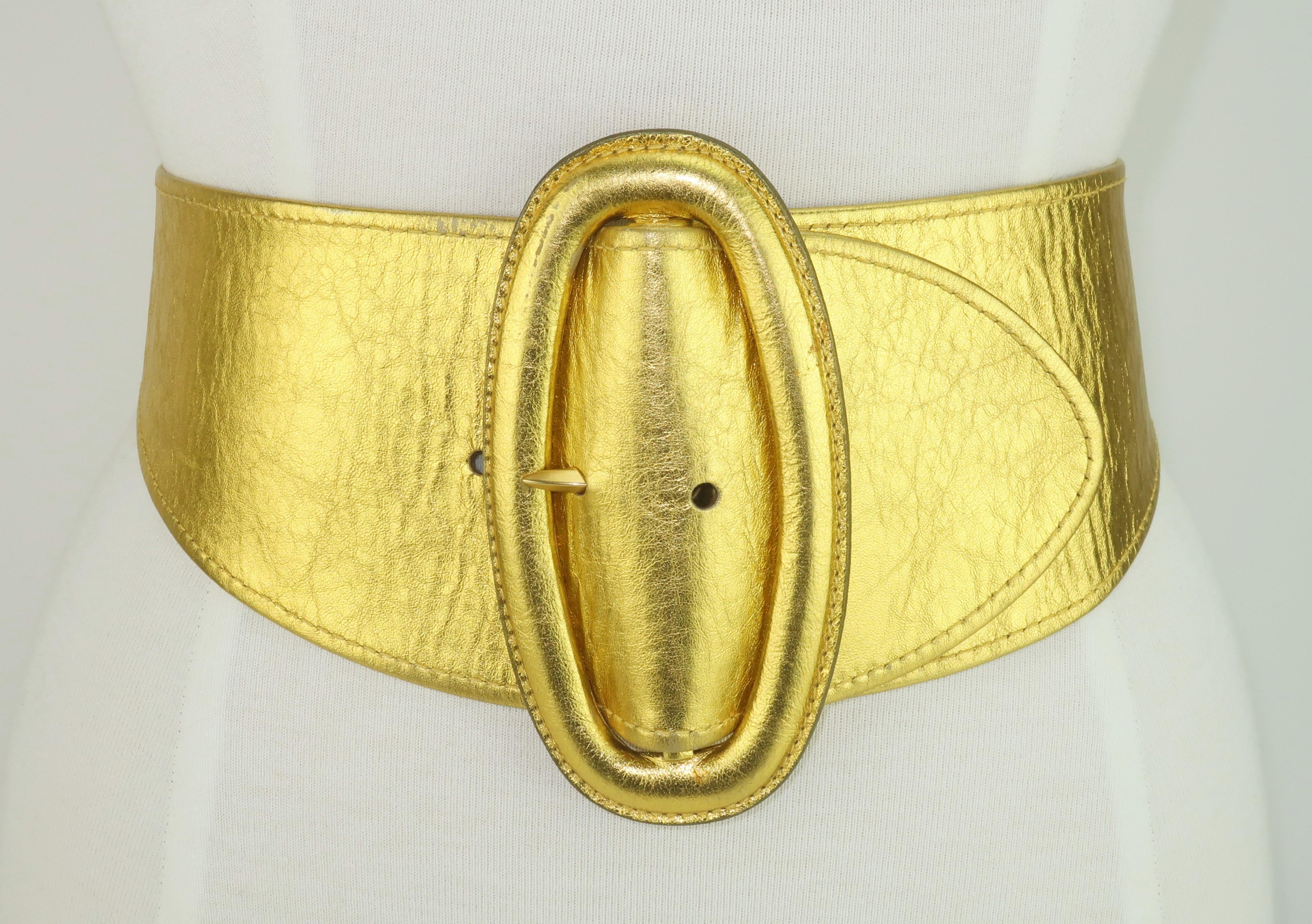 Be a fashion superhero with this strikingly wide gold leather belt from Donna Karan. The 1980’s sculptural silhouette accents the elongated oval buckle which tapers at the back. Marked a size 'Small' and made in Italy ... a true wardrobe essential