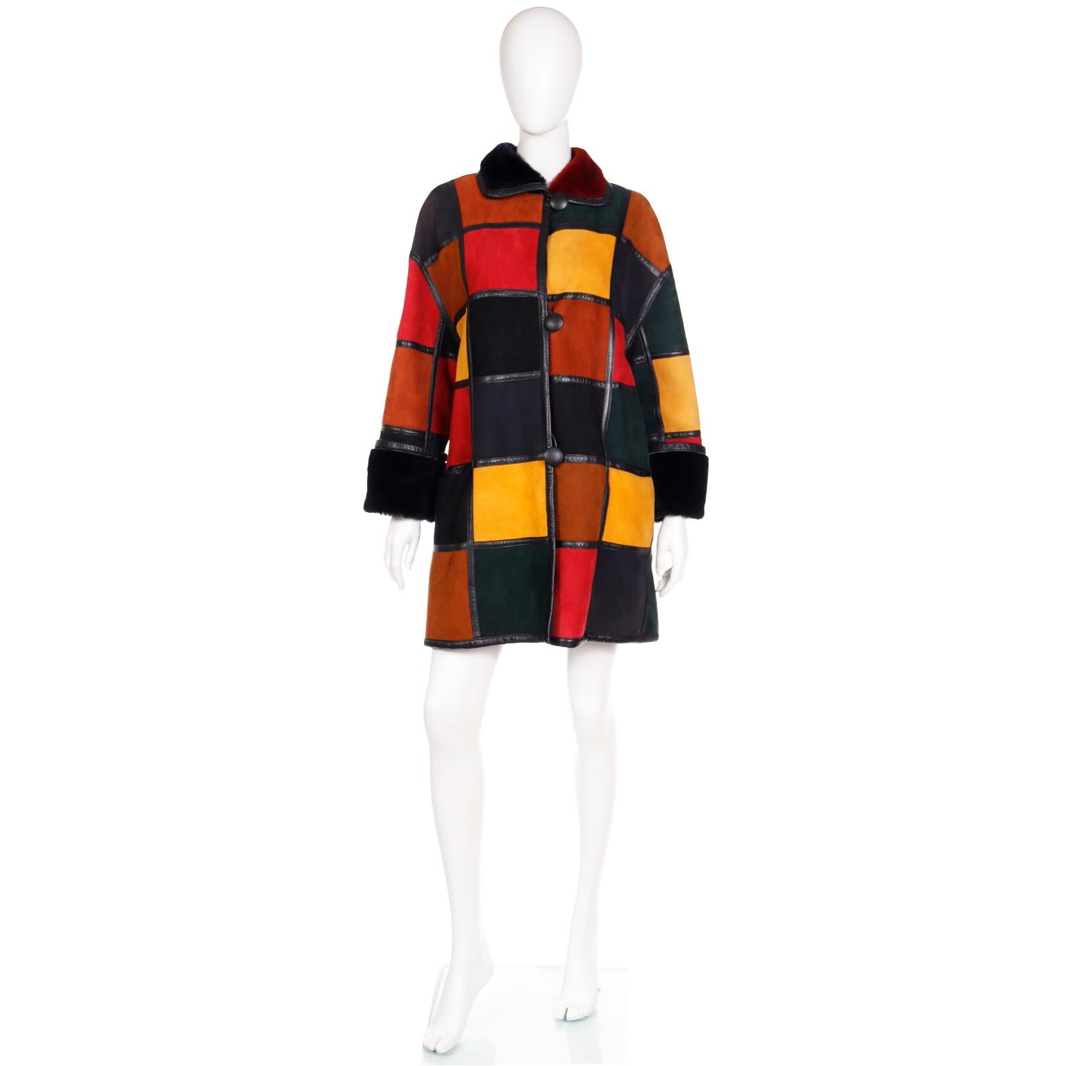 This breathtaking vintage Donna Karan coat is in a patchwork style with blocks of color in shades of rusty orange, red, black and yellow, defined by black leather. trim. One side of the coat is in a luxurious lamb shearling and the other is in a