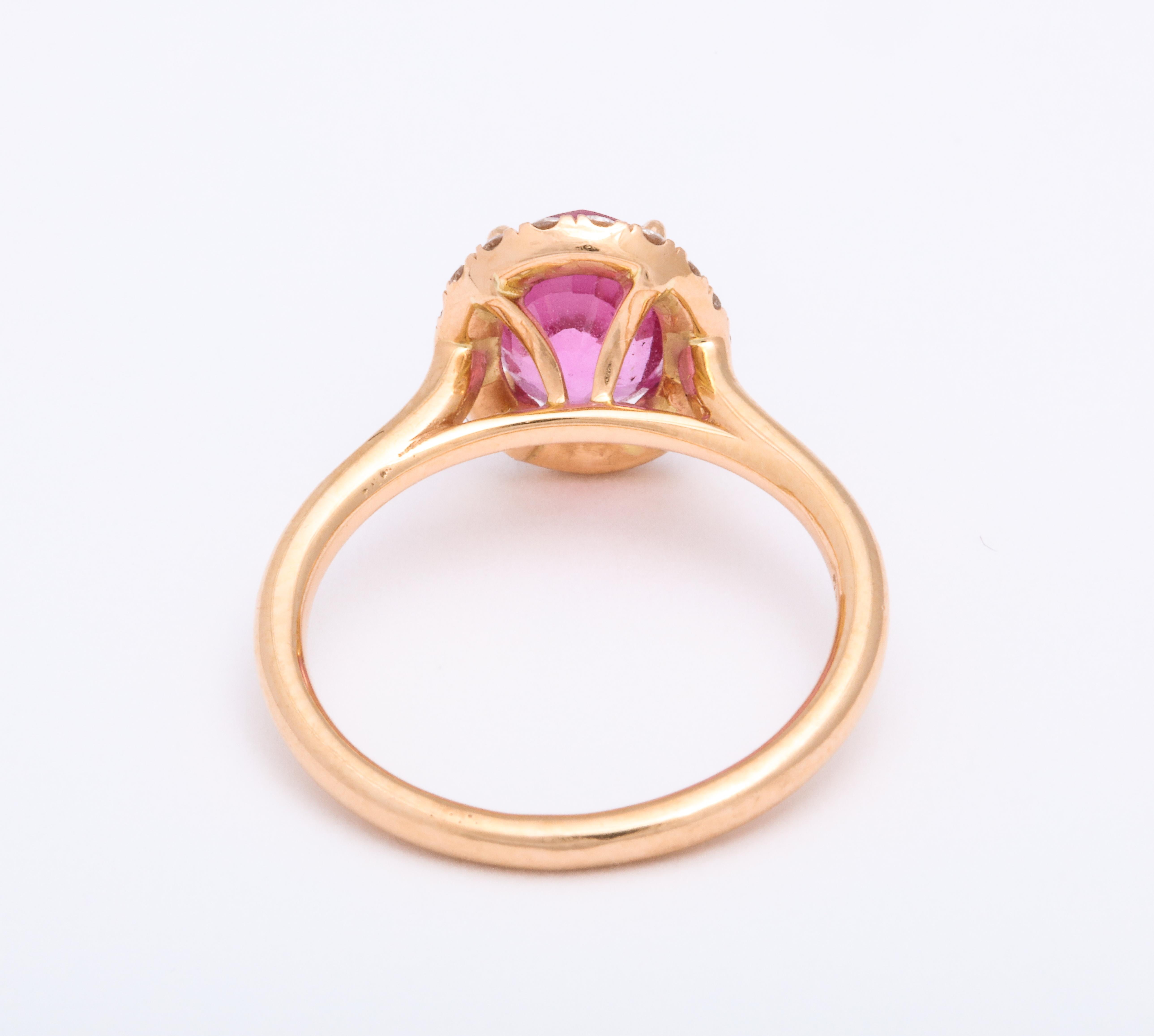 A ring set in 18 karat pink gold featuring a 2.24 carat oval vivid pink Madagascar sapphire. Surrounded by round brilliant diamonds with a total weight of 0.27 carats. Ring size 6. 
