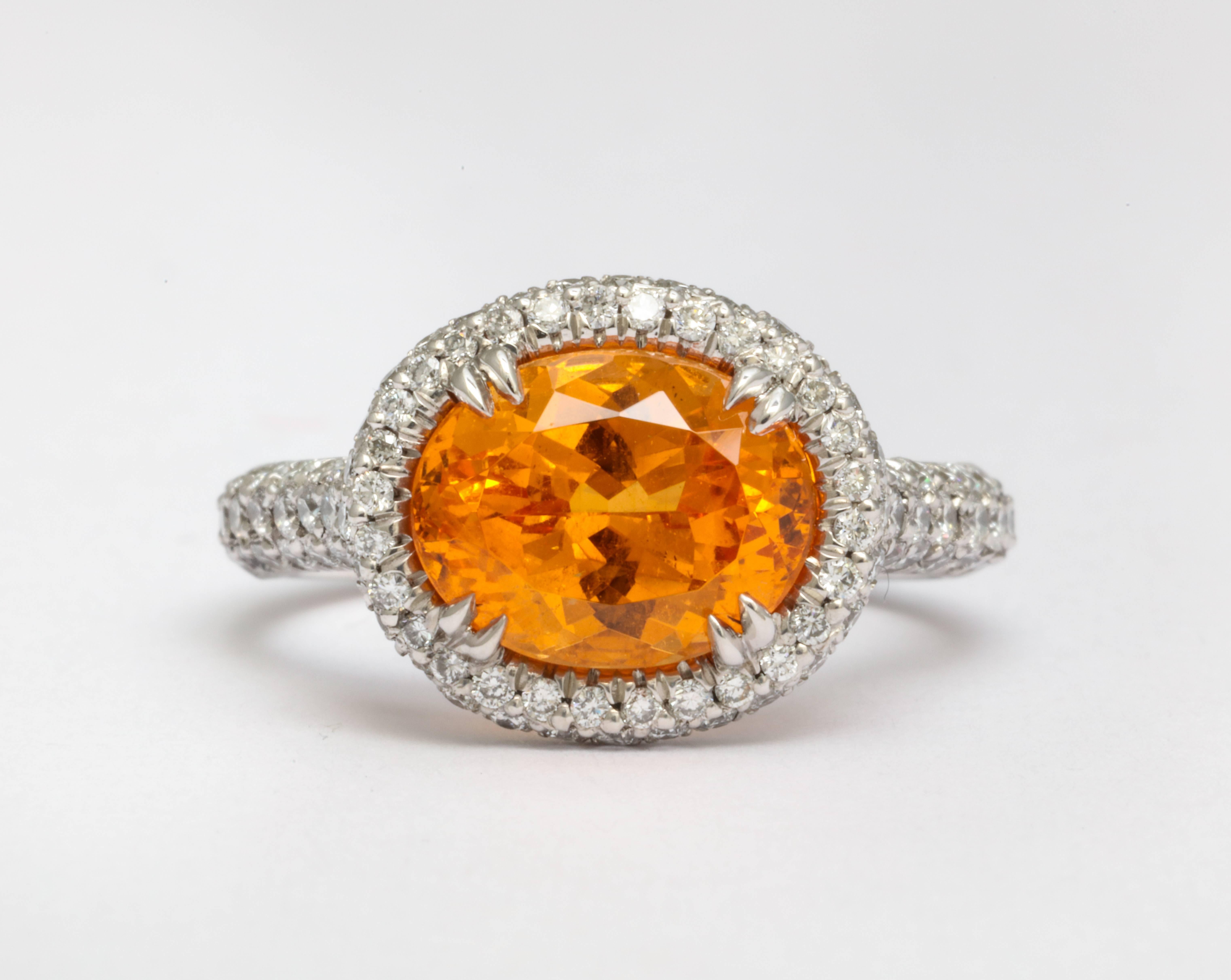 A vivid orange, crystal clean garnet gem. Skillfully crafted platinum ring featuring an oval brilliant cut 3.99 carat mandarin garnet.  Also known as Spessartite, with micro pavé-set diamonds for a rolled affect setting. Total weight of diamonds is