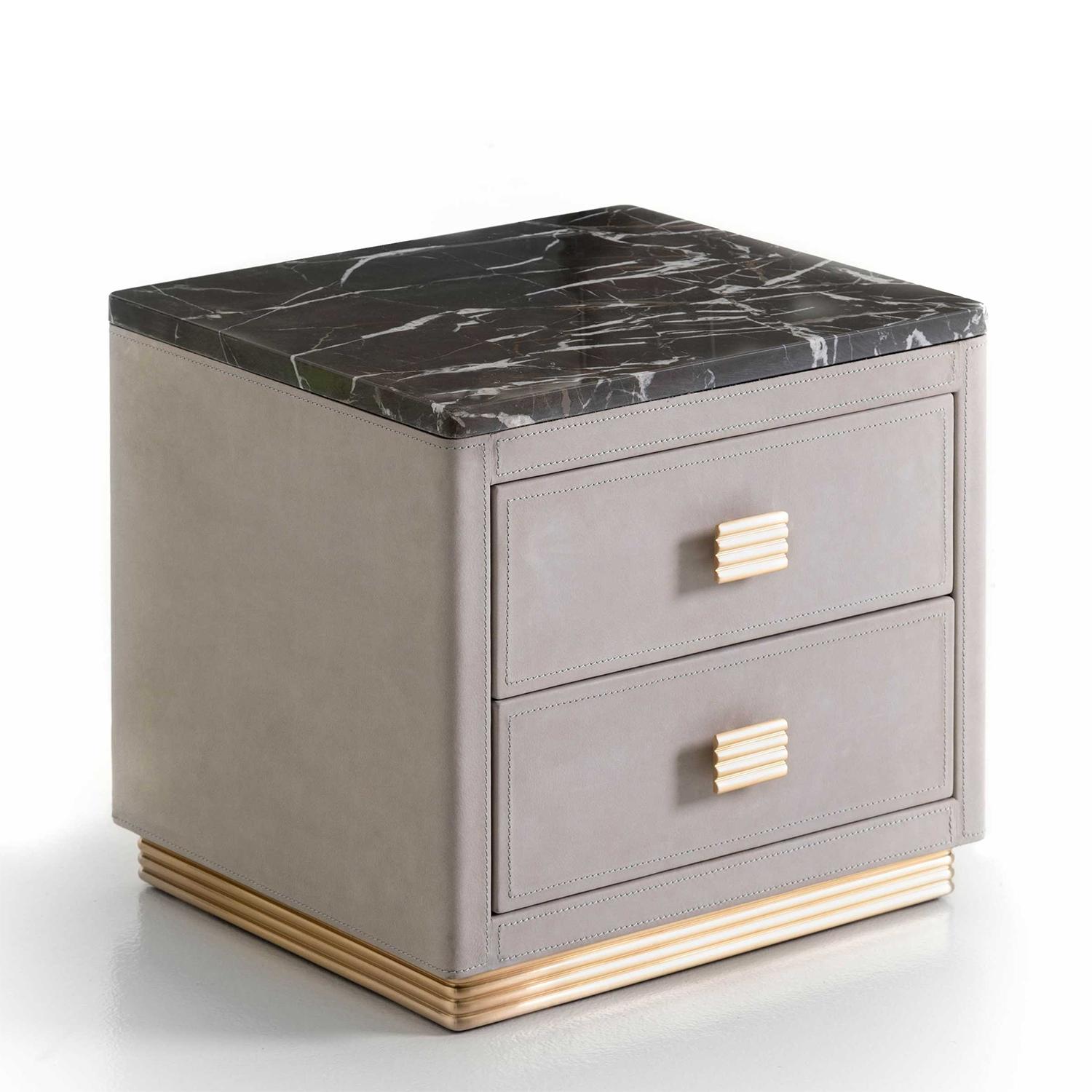 Table de nuit Donovan avec structure en bois massif, 
recouvert de cuir suédé véritable gris clair
et avec un plateau en marbre emperador foncé. Dont
2 tiroirs avec système de glissement facile et 2 poignées
en finition laiton poli. Table de