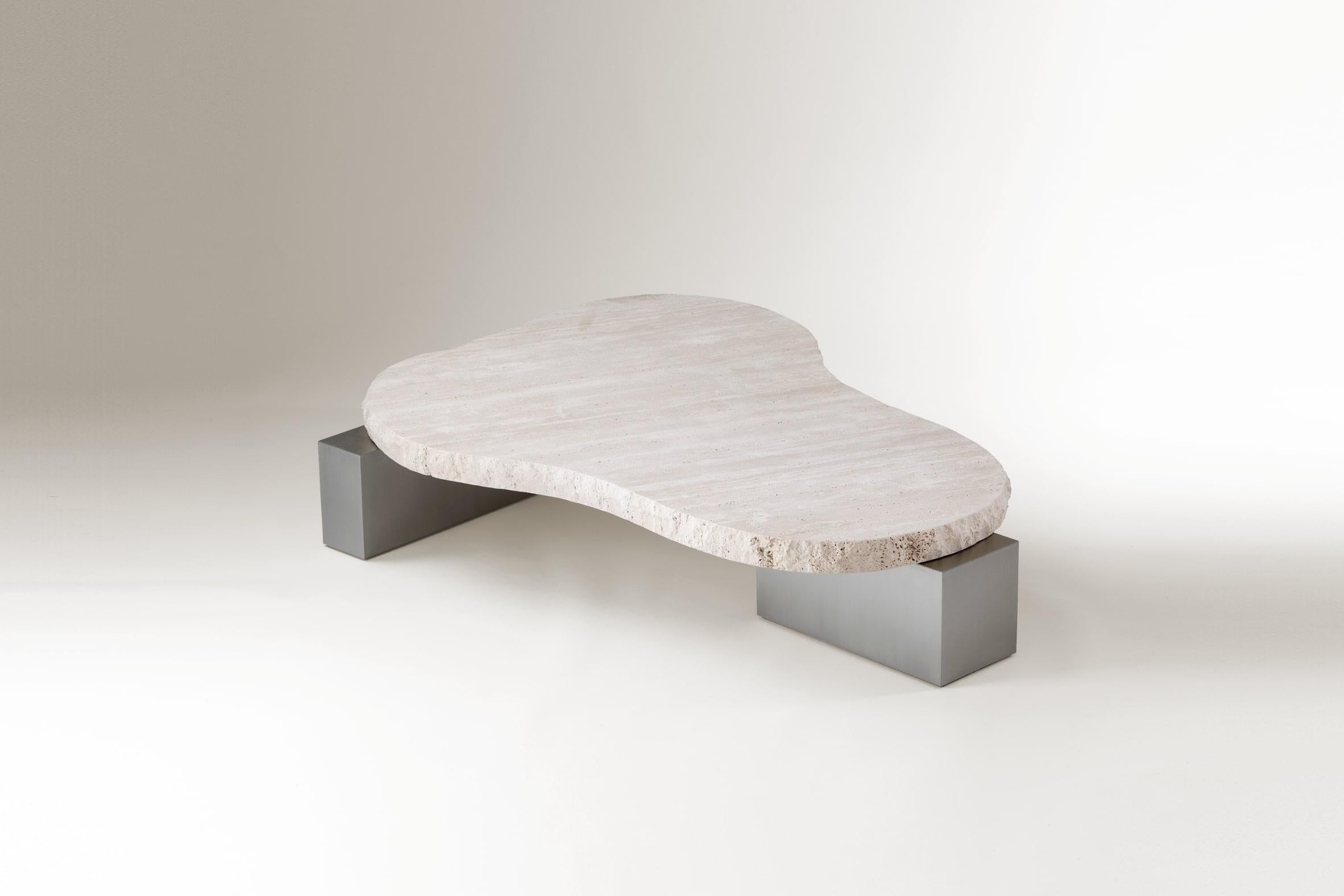 A harmonious exploration of contrasts, the On the Rocks table bridges the organic and the futuristic. With a hand-hammered travertine top that exudes raw, natural beauty and a sleek nickel base that reflects modern elegance, this sculptural table