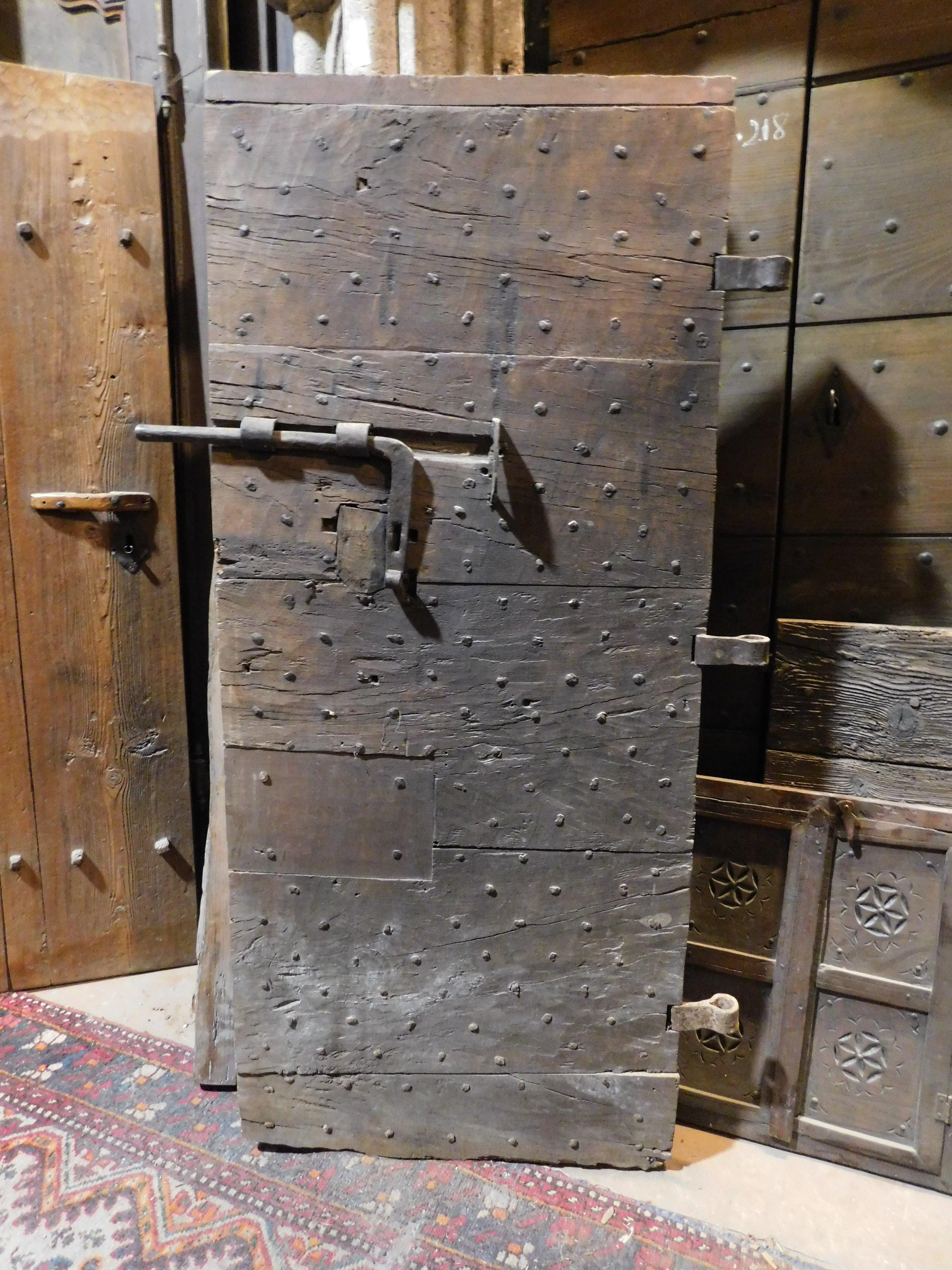 Ancient door with nails, coming from an old Italian prison, built with studs and solid oak wood, still retains the irons and the original latch, smooth back with horizontal bands, origins from the women's prison of Saluzzo (northern Italy), 19th