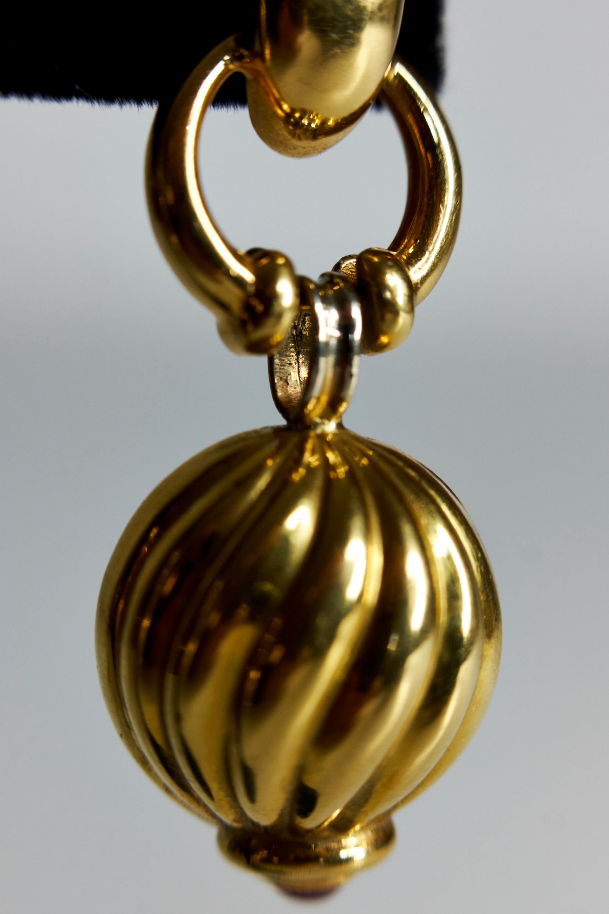 Door knocker earring pendants in 18k yellow gold with gold hoops leading to ribbed hanging orbs, each terminating with ruby cabochon finial. White gold connectors provide wonderful movement to the earrings which swing gently on the wearer. 

Length