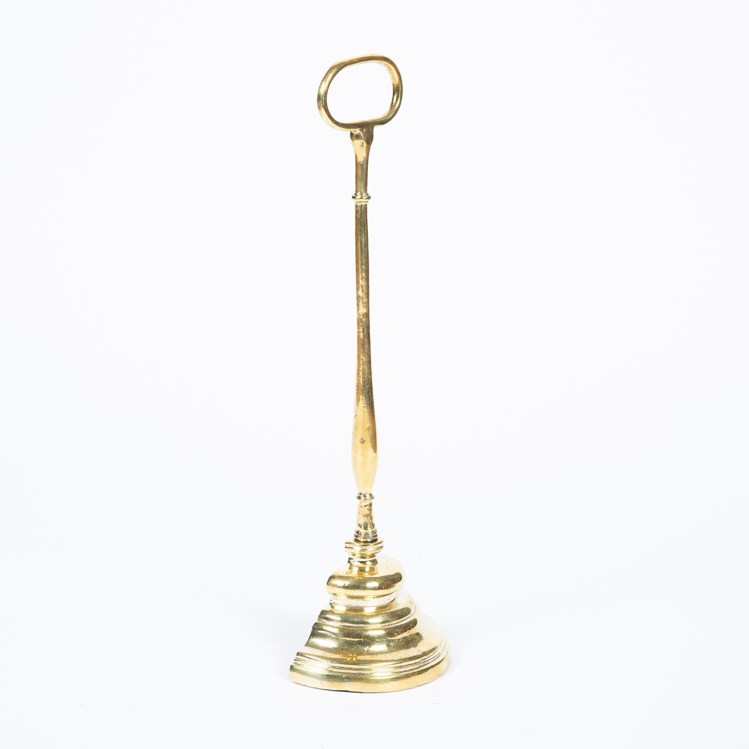 A brass door porter or door stop, with loop handle and stepped weighted base.