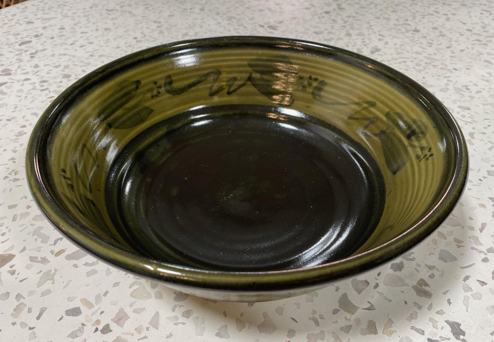 A beautifully designed and gorgeously glazed large bowl by famed Mexican-American California studio art potter Dora De Larios.   The work features hand-painted designs with flowers and sumptuous Fall green and brown colors.    The glaze radiates in