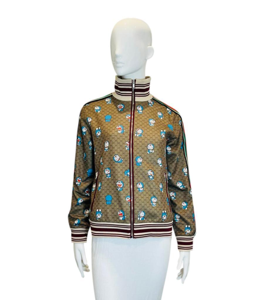 Doraemon X Gucci Fujiko-Pro 'GG' Monogram Track Jacket

Brown jacket with all-over Fujiko-Pro Doraemon figures print in blue.

Detailed with 'GG' Supreme pattern and signature Web-stripe trim.

Featuring ribbed neck, cuffs and hem with centre zip