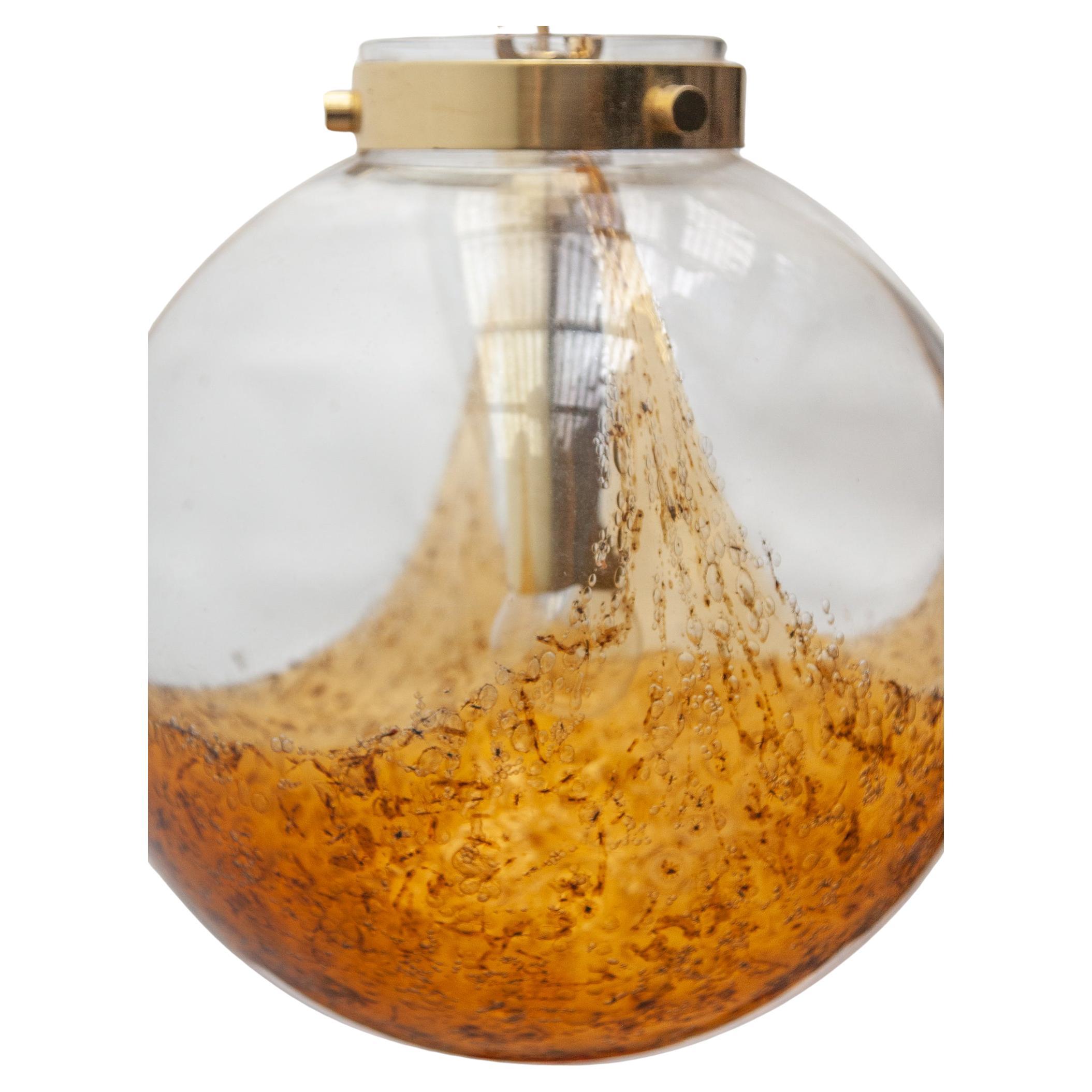 Beautiful exceptional glass globe pendant in the color of deep amber in contrast to clear glass attached to a brass chain. A typical 70s design pendant what will match in any contemporary interior.