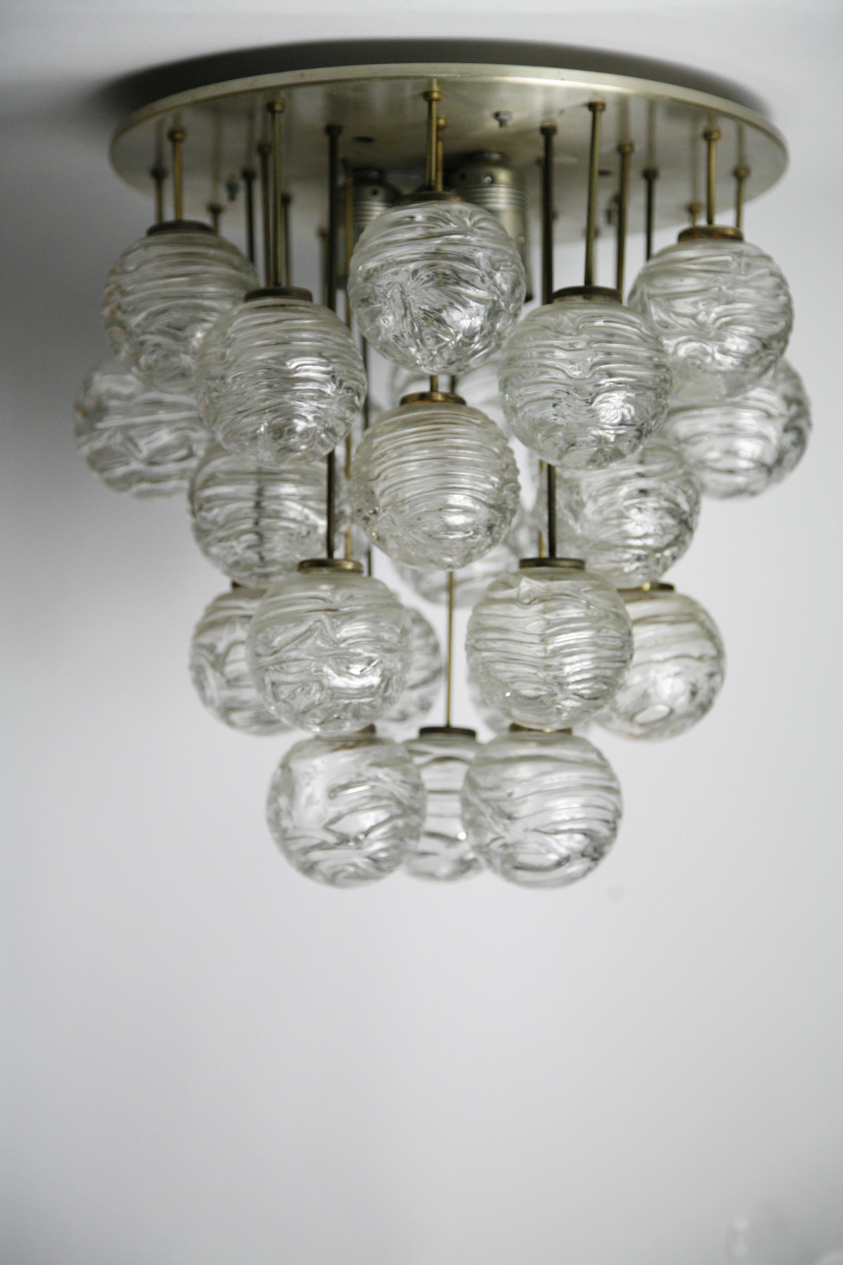 A Doria flushmount, aluminium frame with 26 individual handcrafted blown glass balls each on a single brass stem.
In the centre of the frame plate is five European sockets that will light up the glass balls, each individual glass ball has a pattern