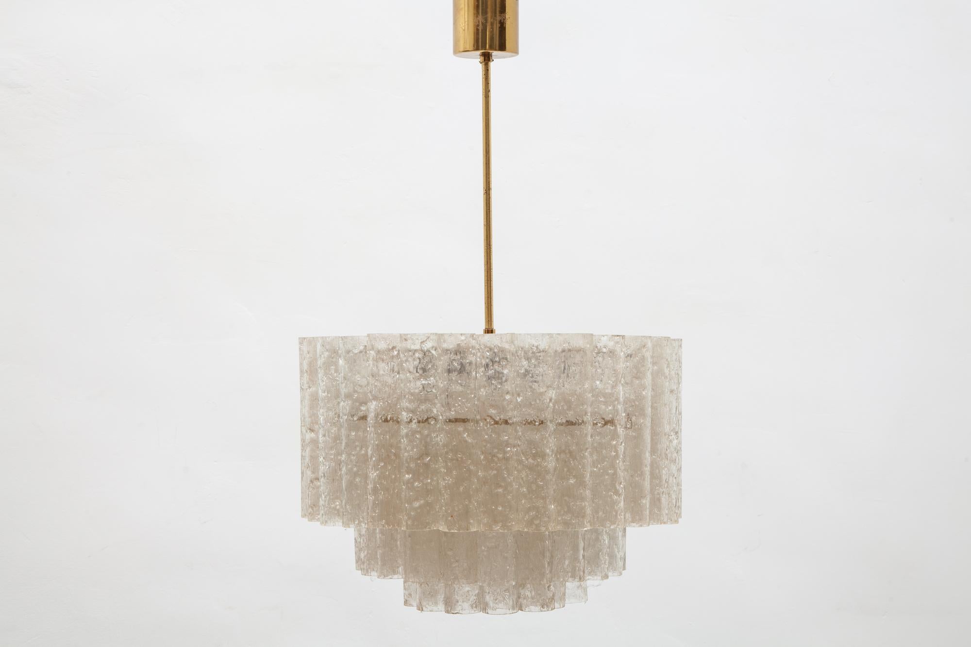 1960s chandelier by Doria, Germany. Three tiers of textured glass tubes on brass and white frame. Lit by 7 bulbs.

Dimensions:
43 W x 65 H x 43 D cm.