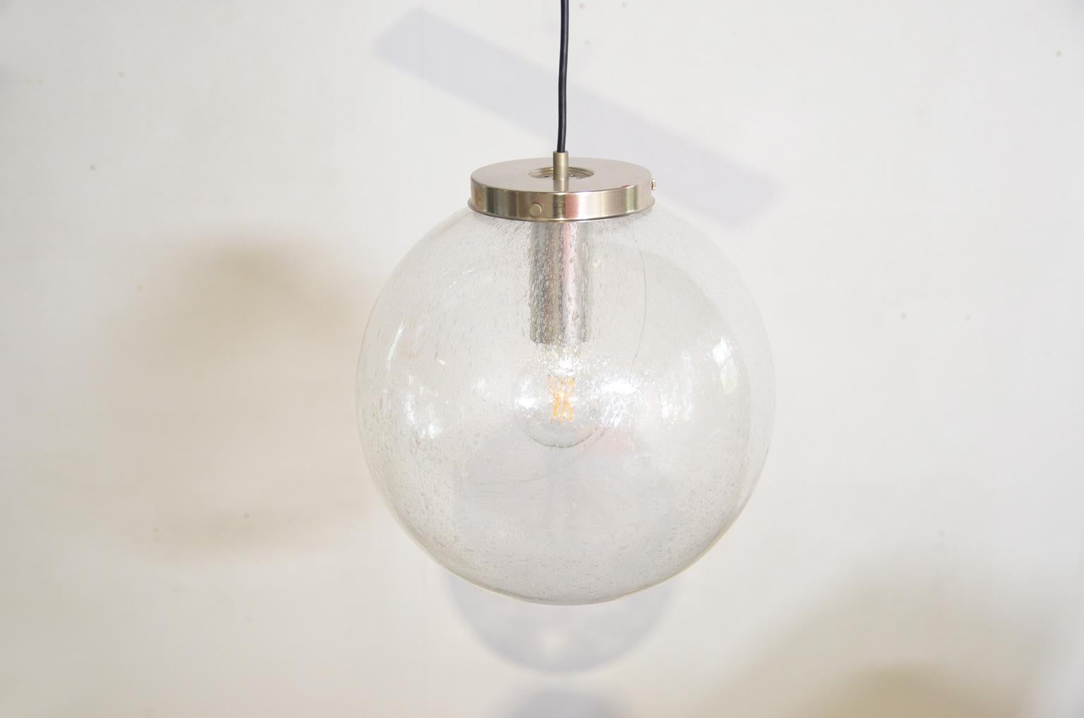 Die mundgeblasene Kugel mit einem Durchmesser von 40 cm verbreitet aufgrund der Struktur des mundgeblasenen Glases ein wunderschön schimmerndes Licht. Die Lampe ist mit einem Doria-Aufkleber versehen und nummeriert (1283). Die Lampe verwendet eine