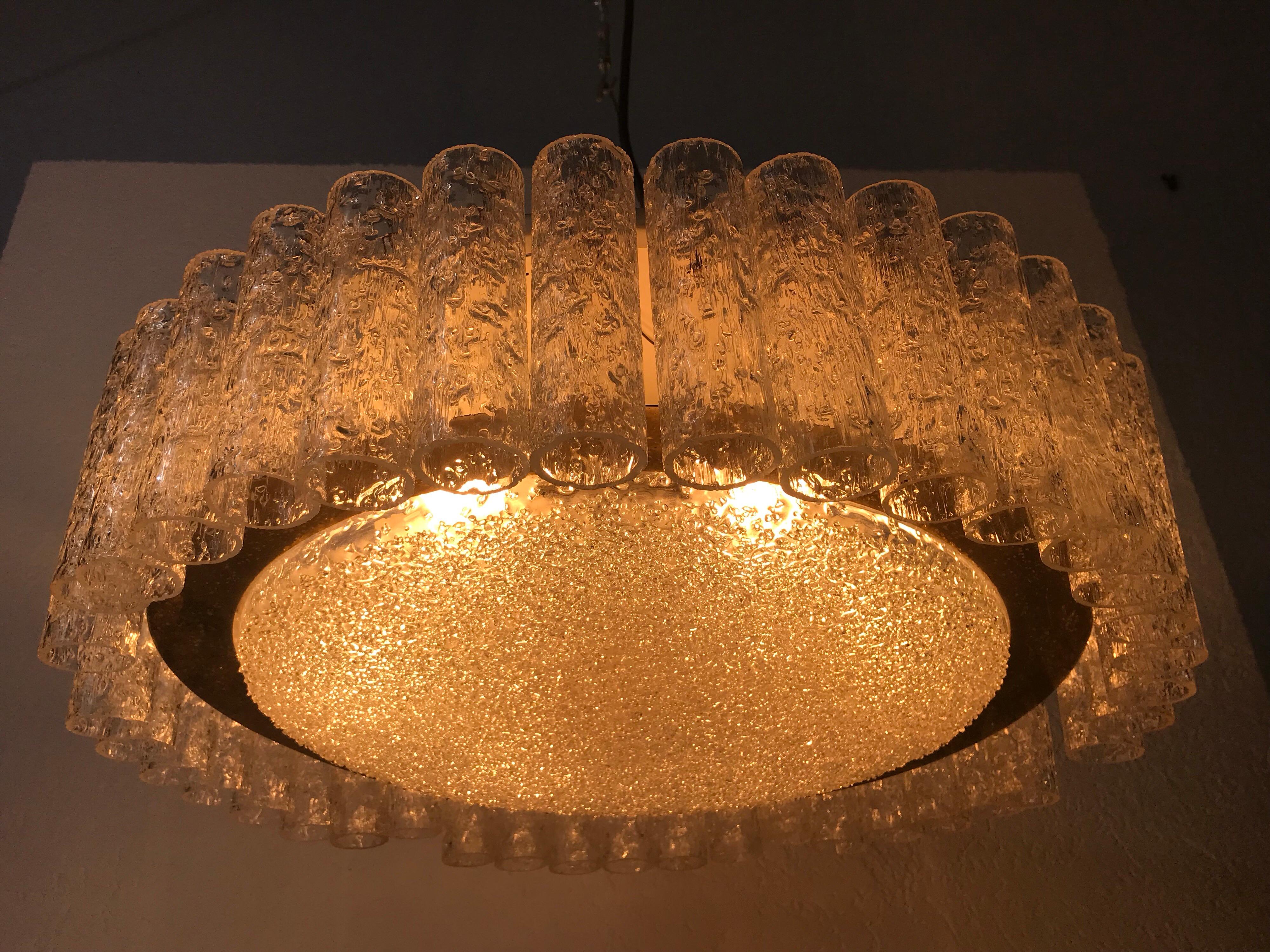 A Doria ice glass chandelier made in Germany in the 1960s. It is fascinating with its many ice tubes. The 40 frosted glass tubes are surrounded by a brass disc with patina. The light has a metal frame at the body.

Measurements:

Height 57