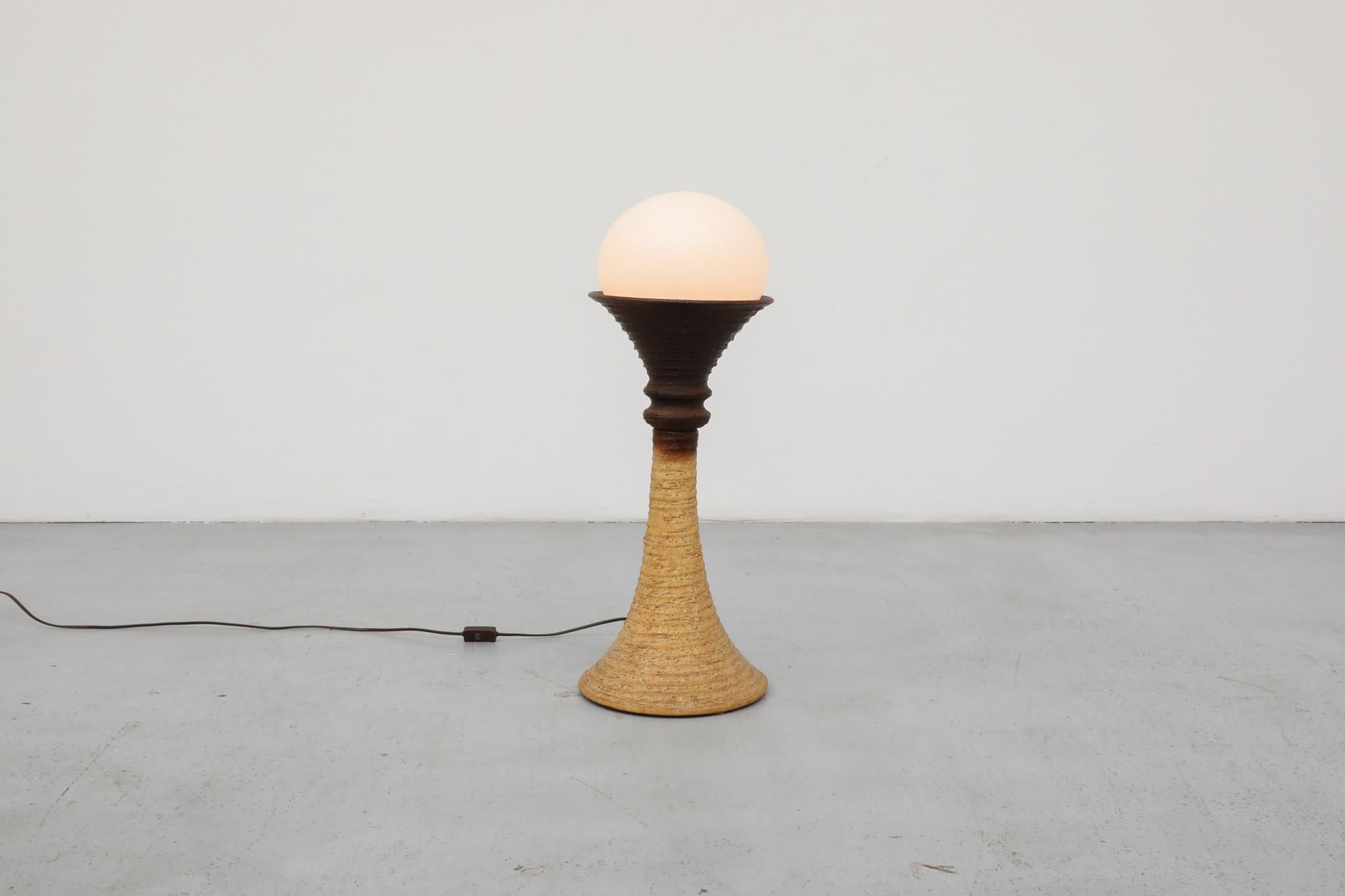 Bellissima lampada da terra del Mid-Century di Doria Leuchten, con un corpo in ceramica a forma di clessidra realizzato in argilla Chamotte. La parte superiore è caratterizzata da un ricco smalto marrone che passa con grazia a una tonalità naturale