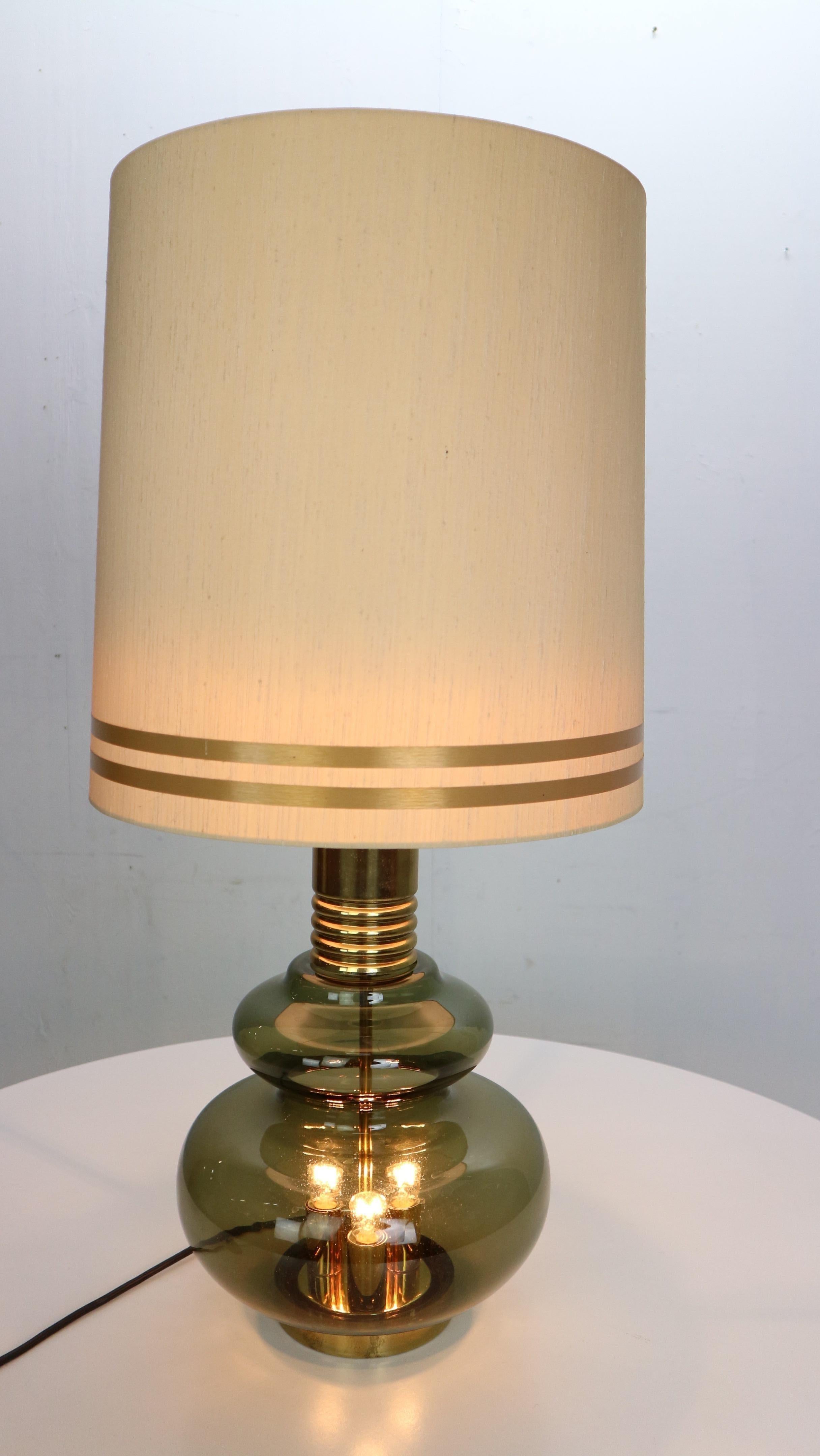 Table lamp manufactured by Doria Leuchten in Germany in the 1960's.
Structure in green glass with brass details. 
Three-lights in the glass bottom and one light under the shade (sand color with golden details), with a light switch you can adjust