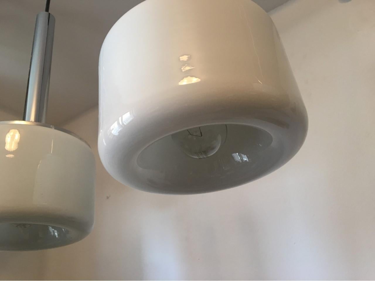 A pair of nice Doria Leuchten of Germany milk glass pendants with chrome holders and black cables. From the 1970s. In good working condition. Each requires E 26 / 27 Edison bulbs up to 100 watts each. Equipped with original 20th century wiring.