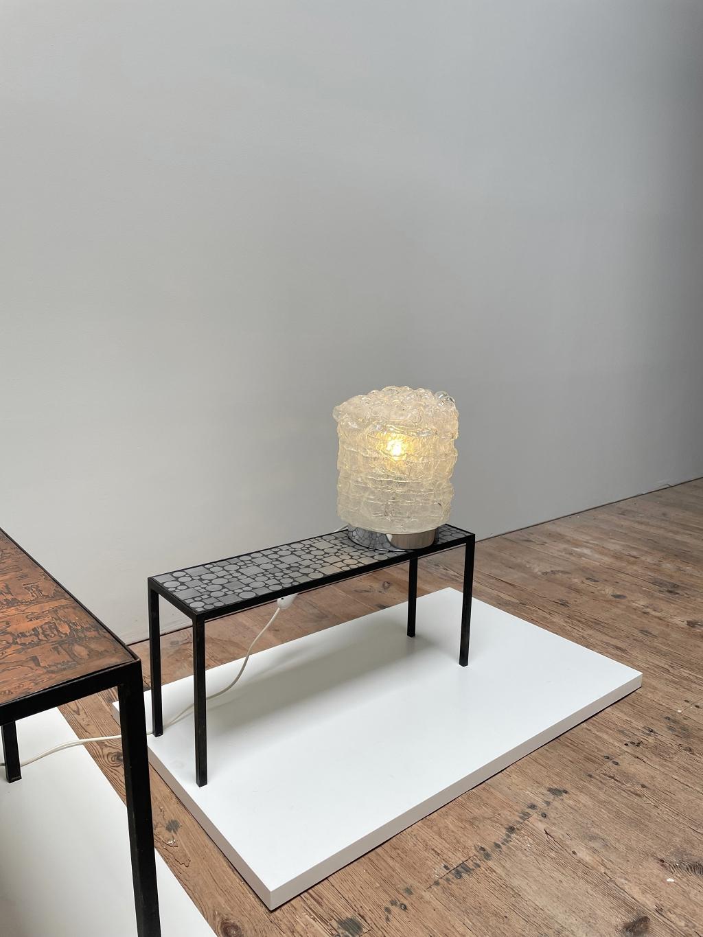Elegante Space-Age-Tischleuchte, hergestellt von DORIA Leuchten in Deutschland. Die Lampe besteht aus einem Metallsockel mit einem mundgeblasenen Lampenschirm, der Luftblasen enthält und für ein sanftes und wunderbares Licht sorgt. Die Lampe ist in