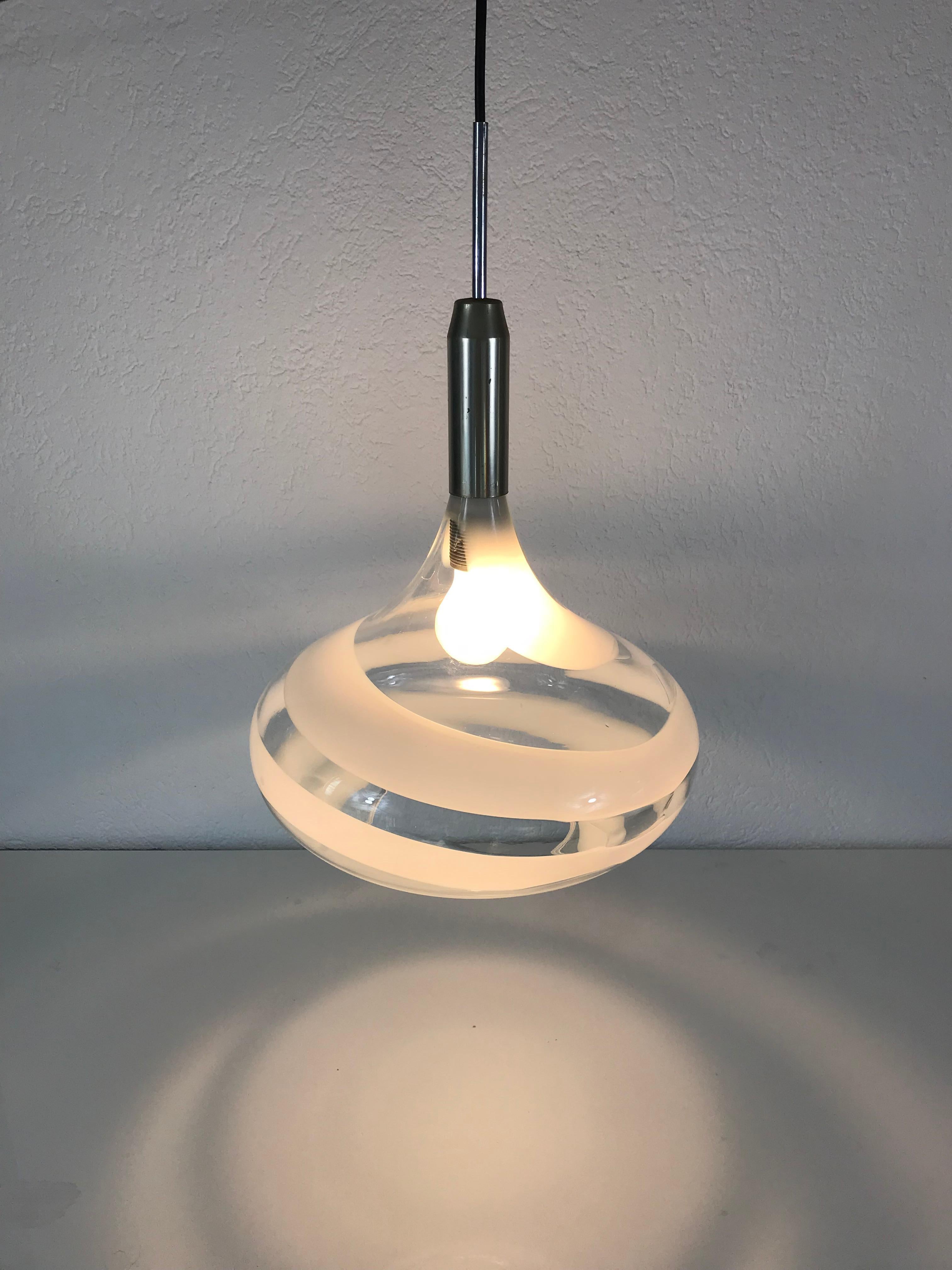 A Doria pendant lamp made in Germany in the 1970s. It is fascinating with its rare glass shape. The glass is transparent and has white spiral ornaments. The top of the light is polished metal.

The light requires one E27 light bulb.