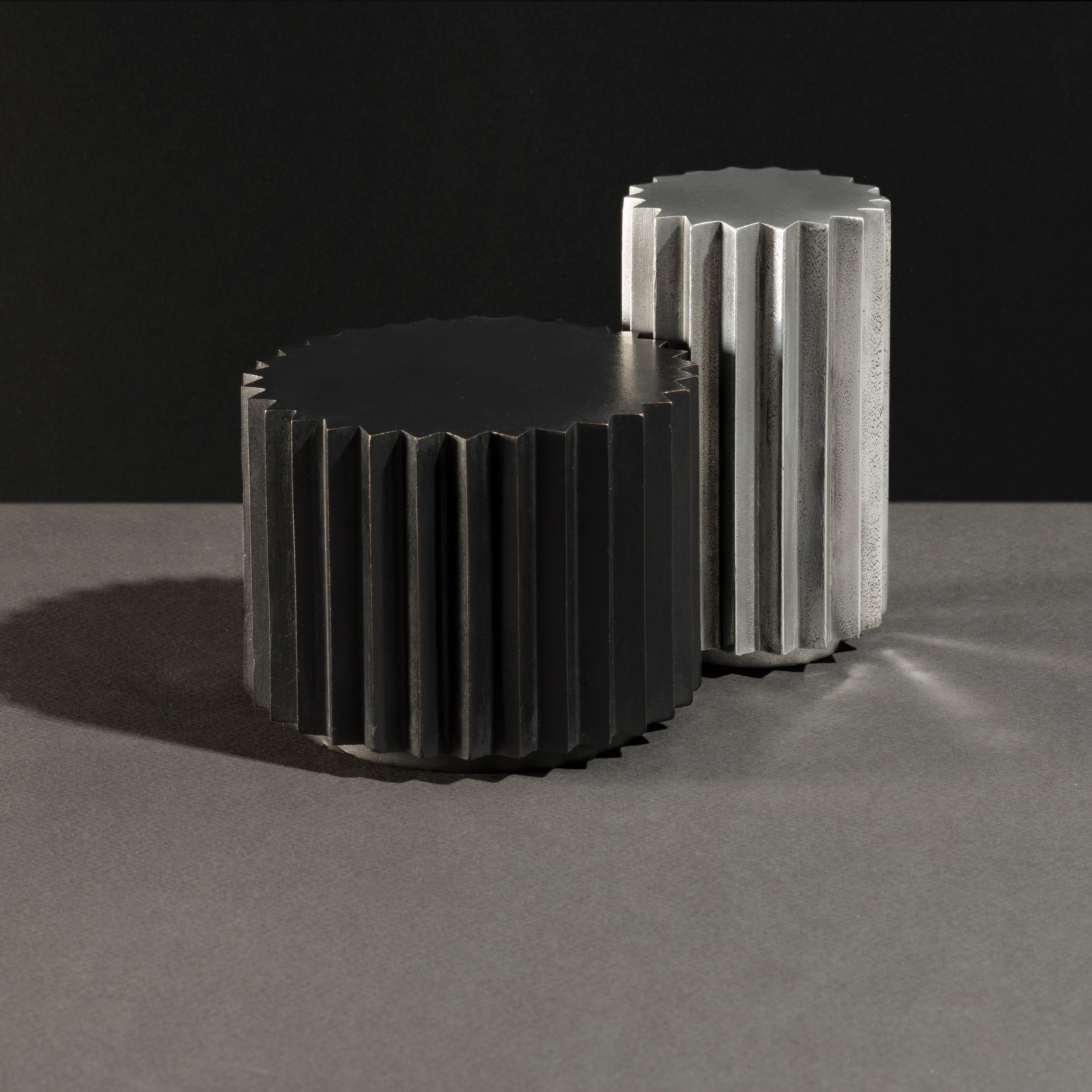 Side tables in cast bronze or aluminum of different diameters and heights that can be combined to create a coffee table. Inspired by Doric columns in Archaic architecture, the extruded multi-point stars have a different finish on each vertical face: