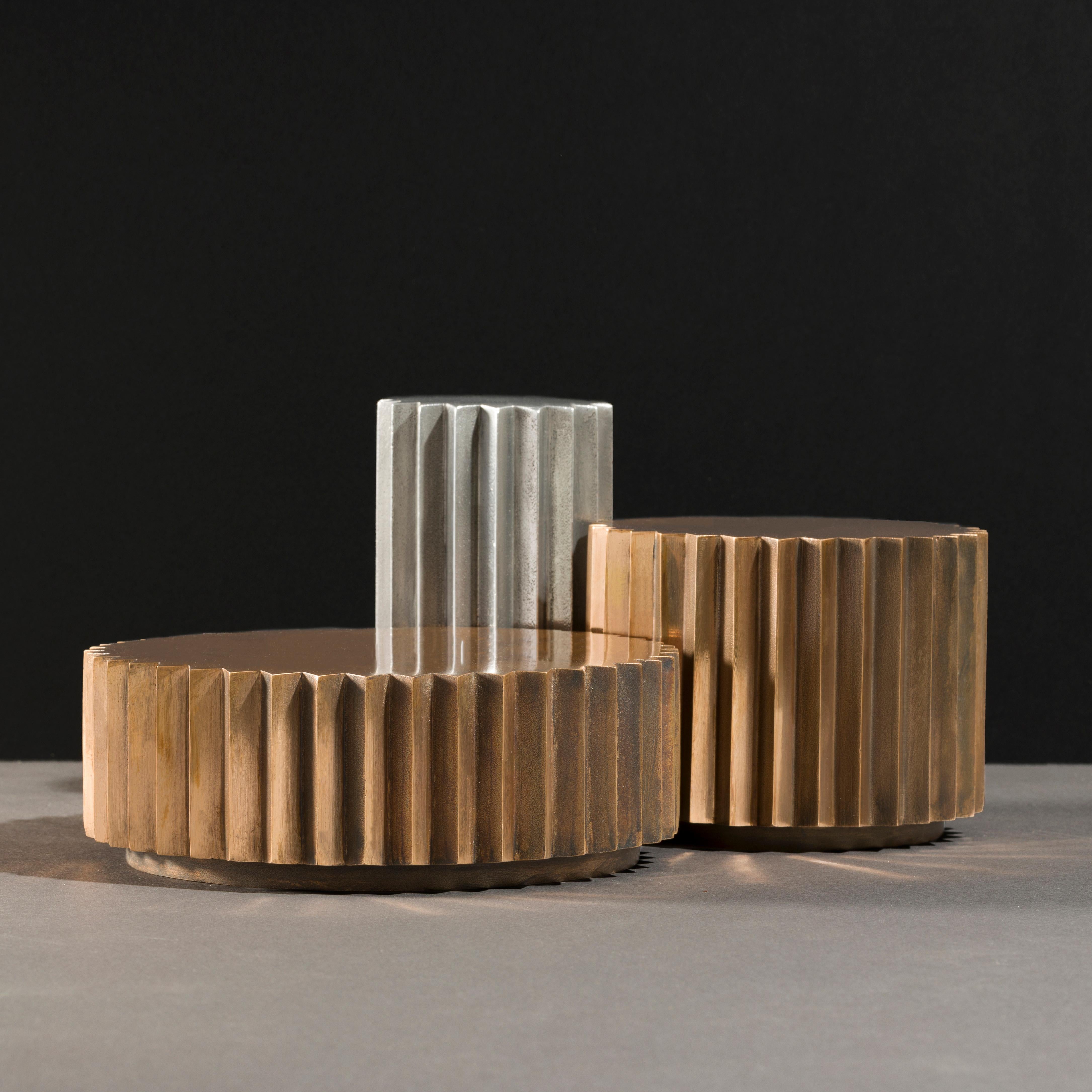 Side tables in cast bronze and aluminum of different diameters and heights that can be combined to create a coffee table. Inspired by Doric columns in archaic architecture, the extruded multi-point stars have a different finish on each vertical