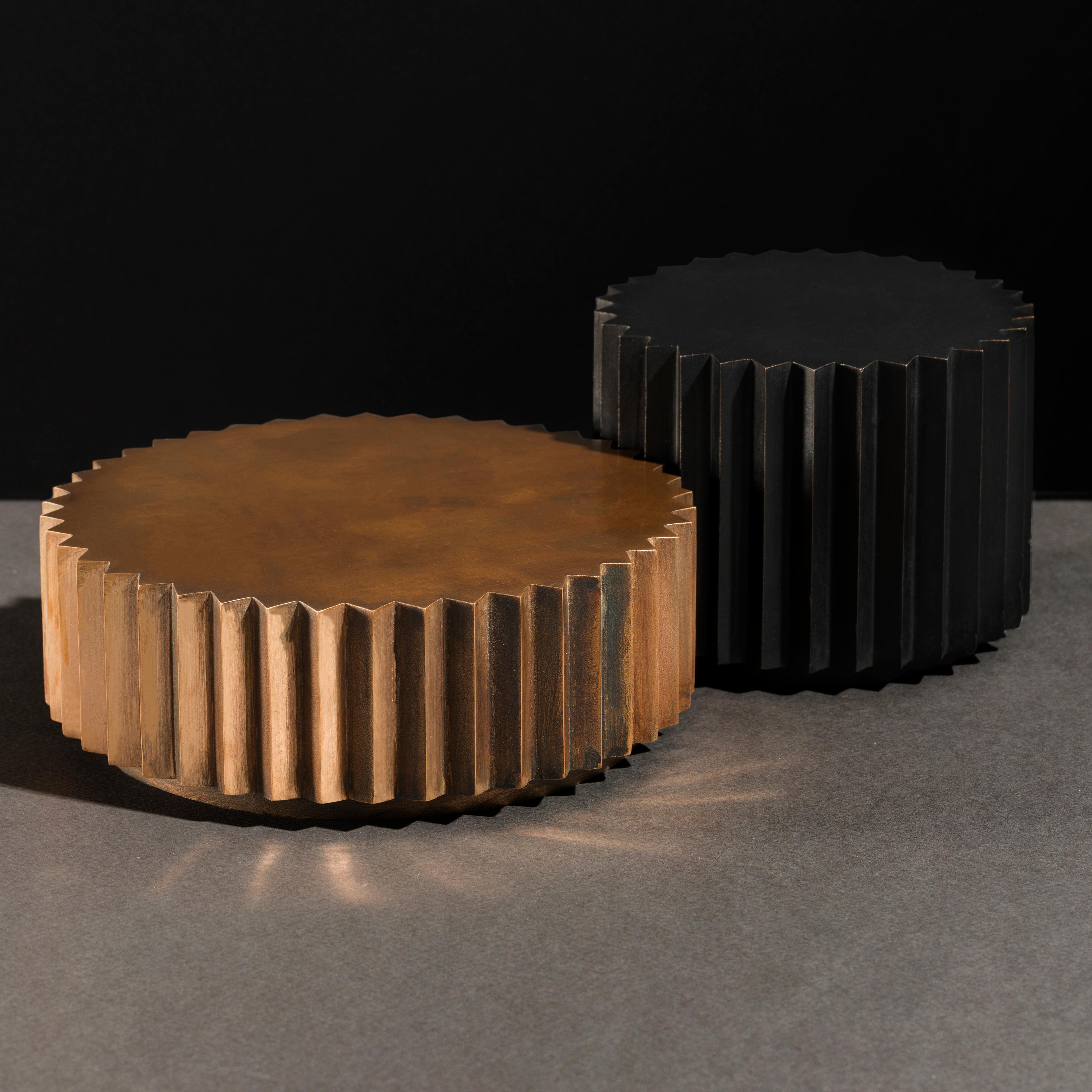 Side tables in cast bronze or aluminum of different diameters and heights that can be combined to create a coffee table. Inspired by Doric columns in Archaic architecture, the extruded multi-point stars have a different finish on each vertical face: