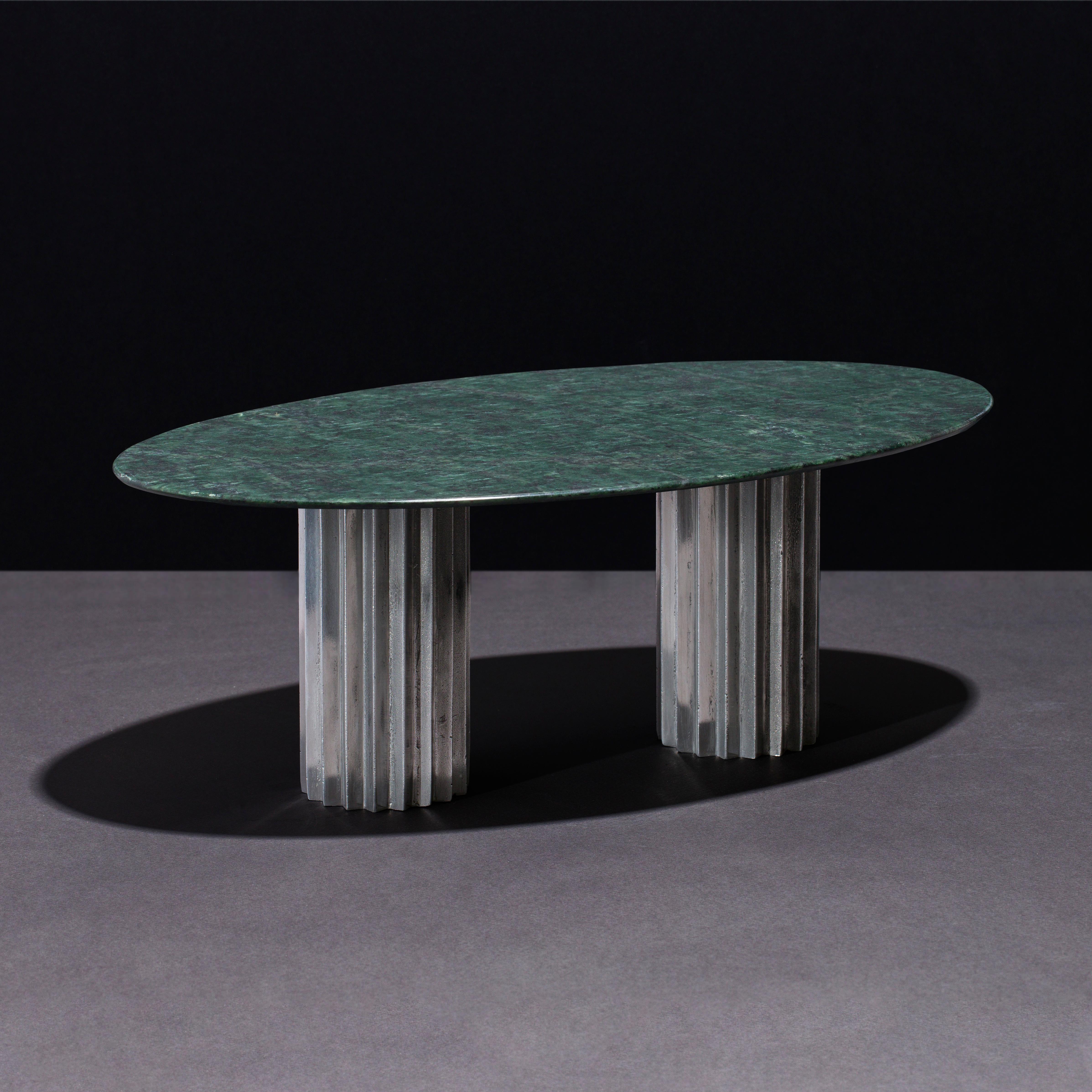 Dining tables with marble tops and multifaceted pedestals in cast bronze, blackened bronze or aluminum. 

Inspired by Doric columns in archaic architecture, the extruded multi-point star pedestals have a different finish on each vertical face: the