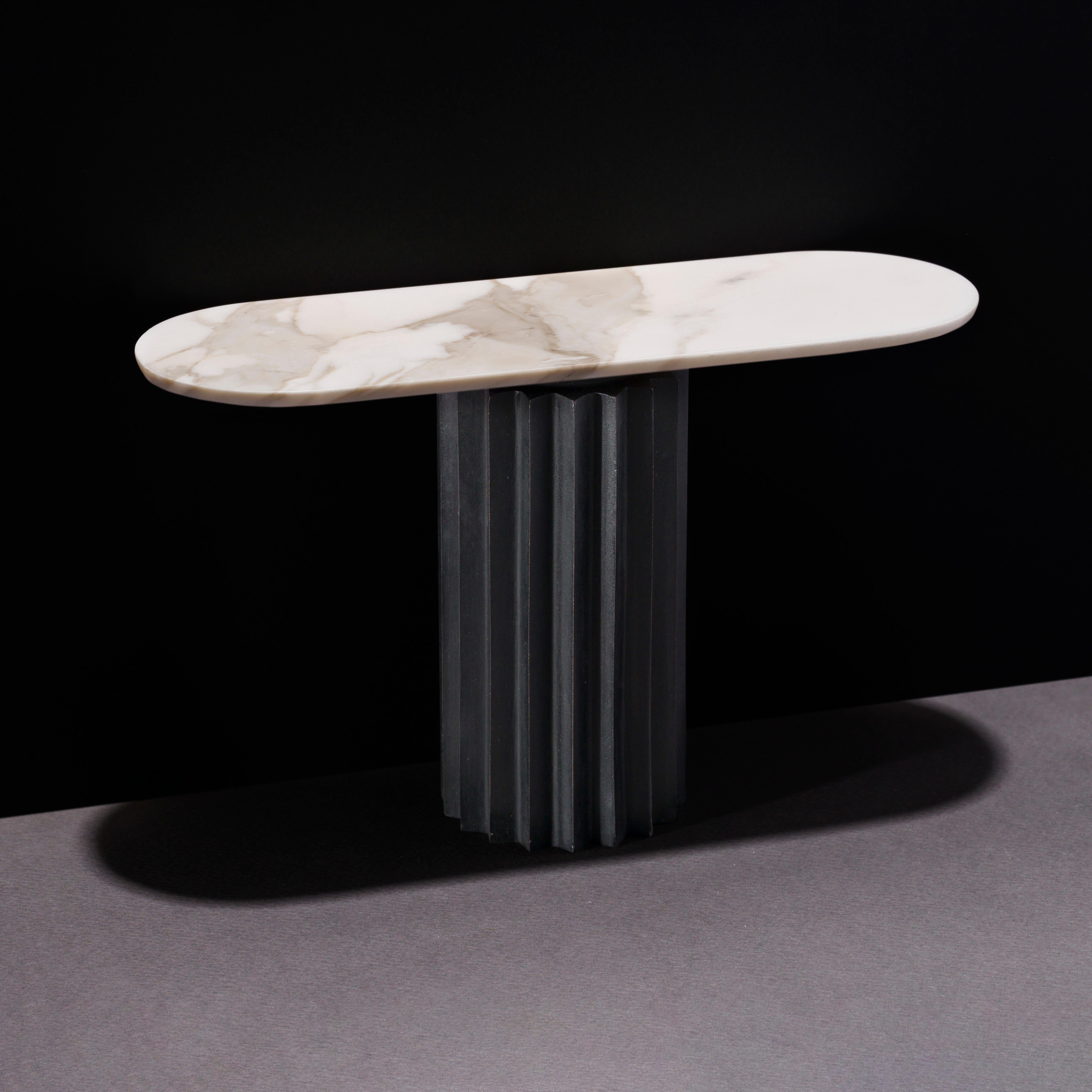 Dining tables with marble tops and multifaceted pedestals in cast bronze, blackened bronze or aluminum. 

Inspired by Doric columns in archaic architecture, the extruded multi-point star pedestals have a different finish on each vertical face: the