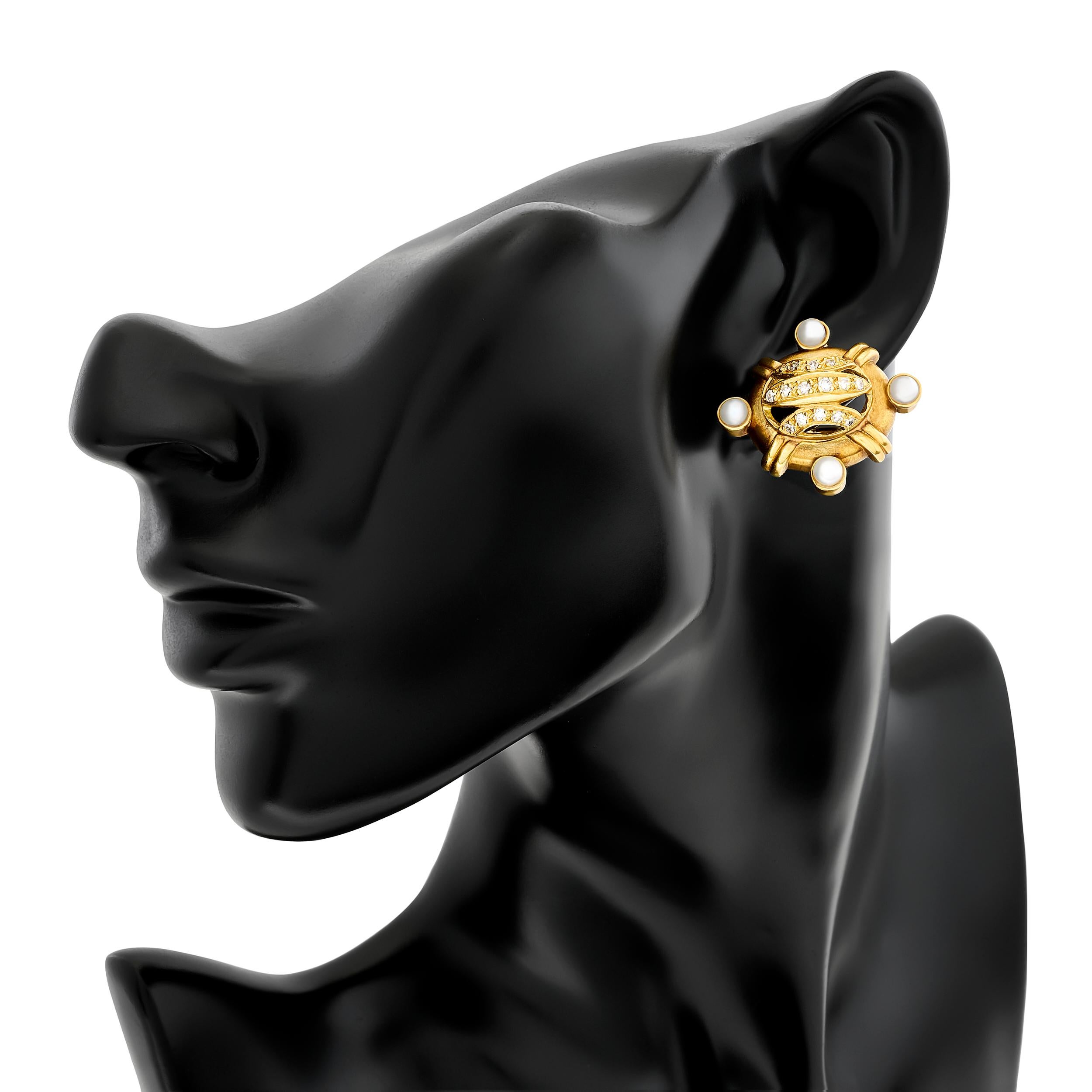 Die Gelbgold-Ohrringe von Doris Panos bestechen durch ihr einzigartiges Design mit Diamanten und Perlen, die in den Himmelsrichtungen angeordnet sind.

Diese Ohrringe haben 32 runde Diamanten mit einem Gewicht von ca. 0,75 Karat, der Farbe H-I und